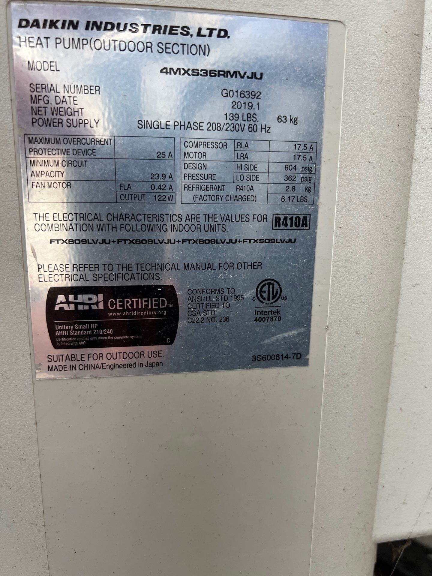 Metal label on a Daikin Industries heat pump outdoor section, with model, serial number, and electrical specifications.
