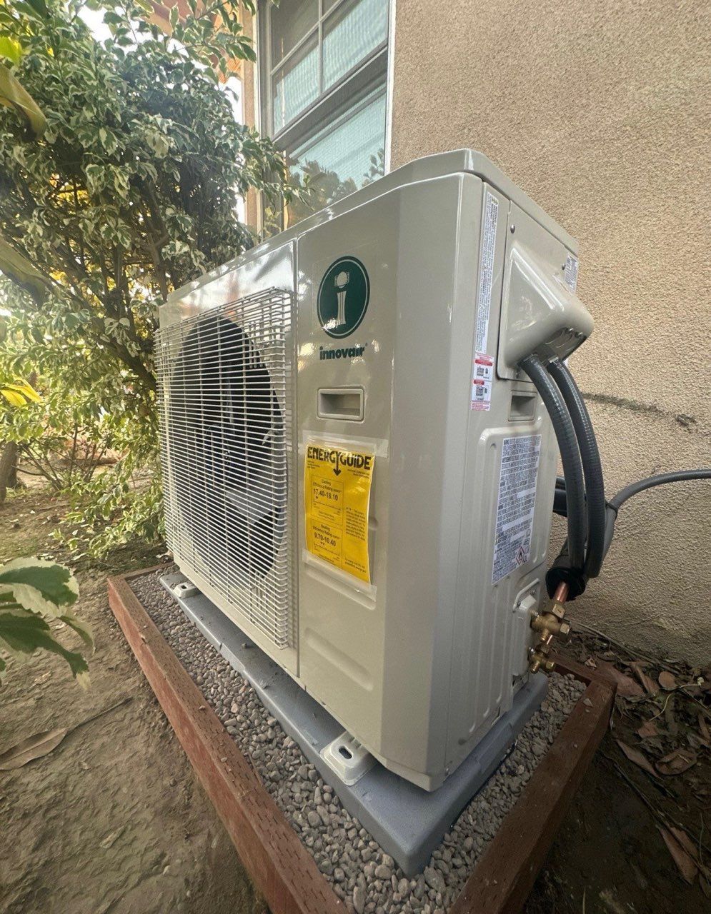 Exterior heat pump unit on a concrete base, mounted near a building.