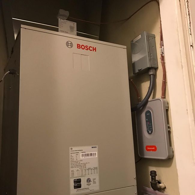 Bosch HVAC unit in a utility closet with a Honeywell thermostat.