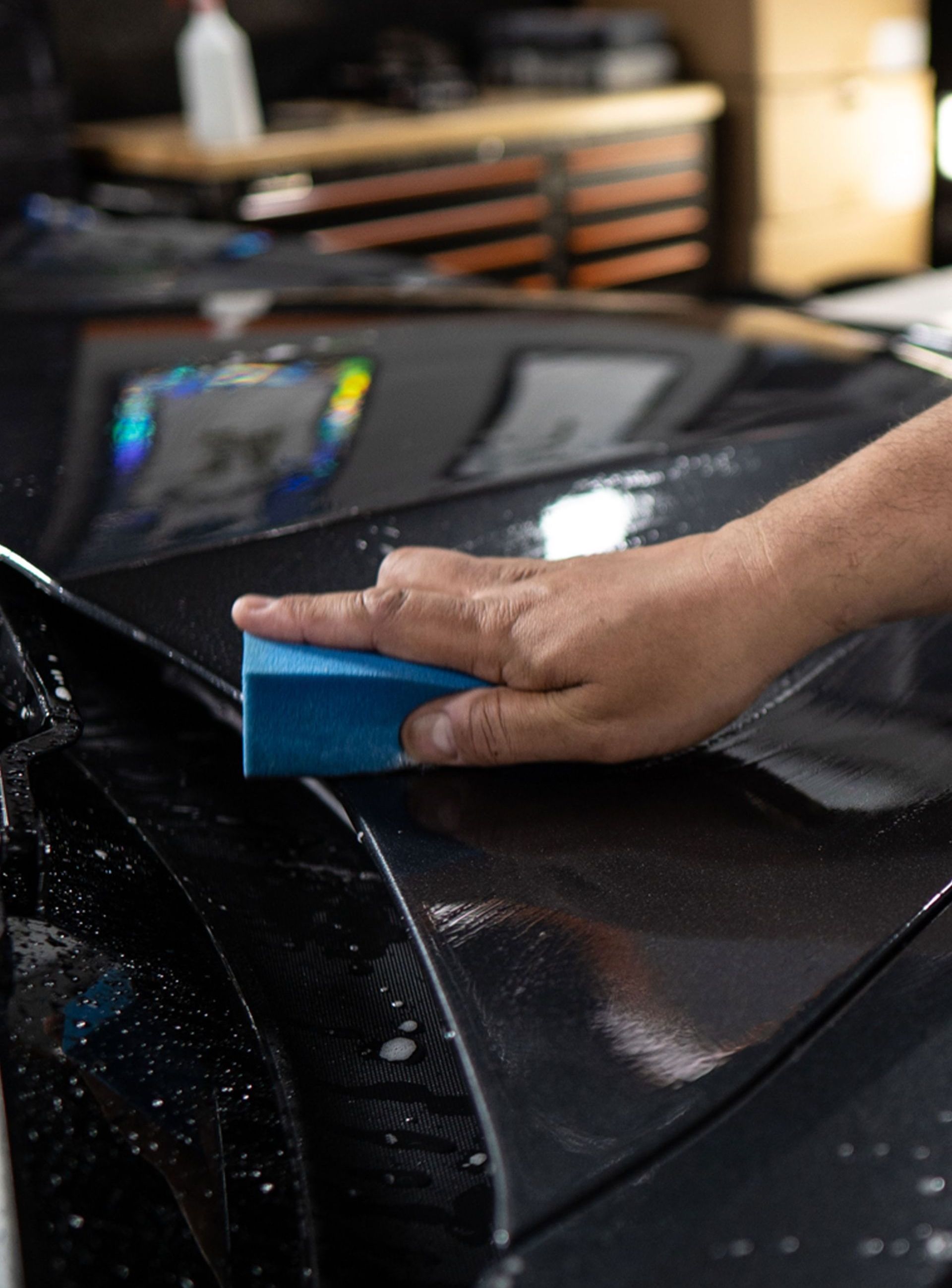 A person is cleaning a car with a blue sponge.