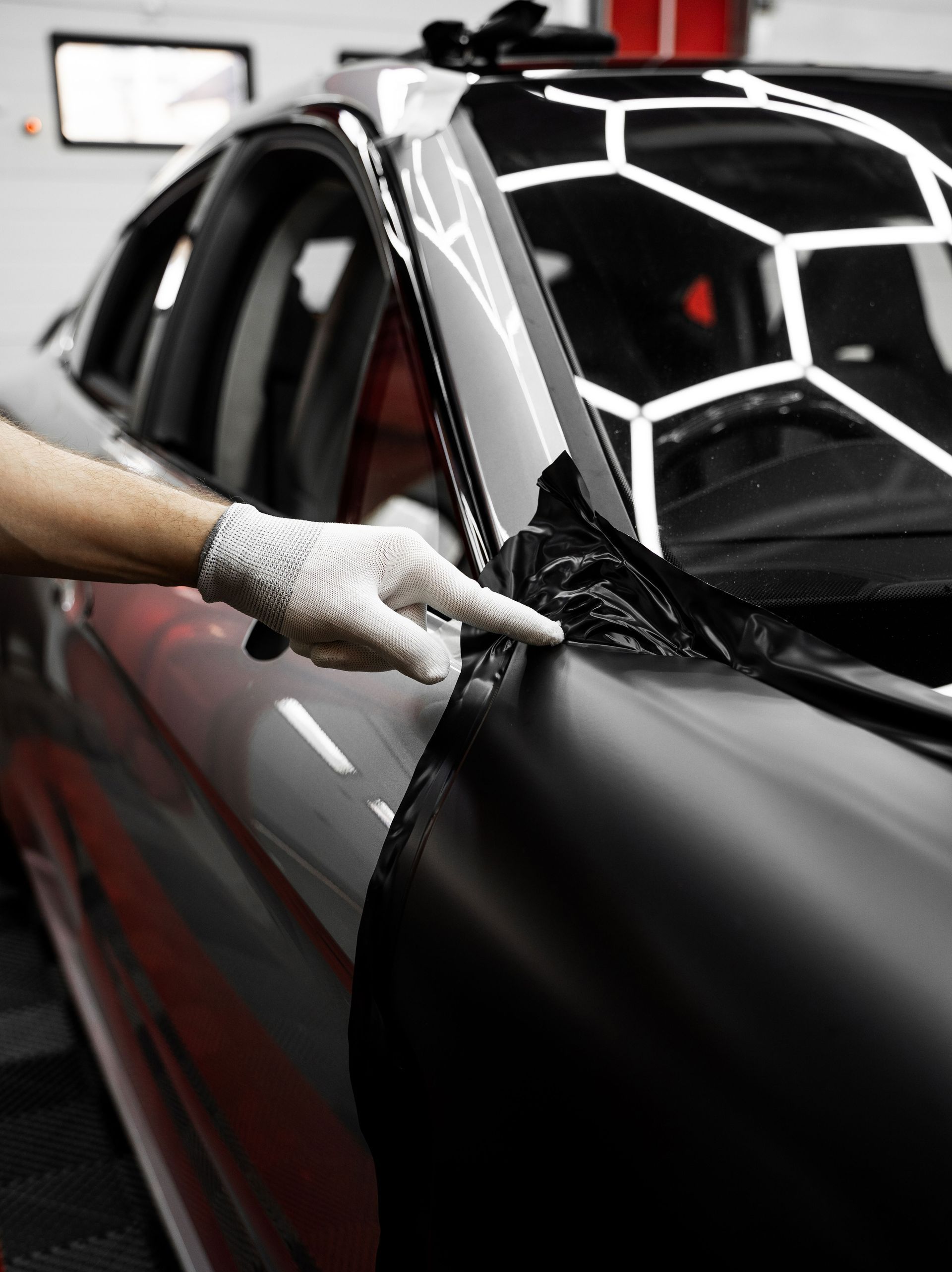 A person is wrapping a car in black ppf.