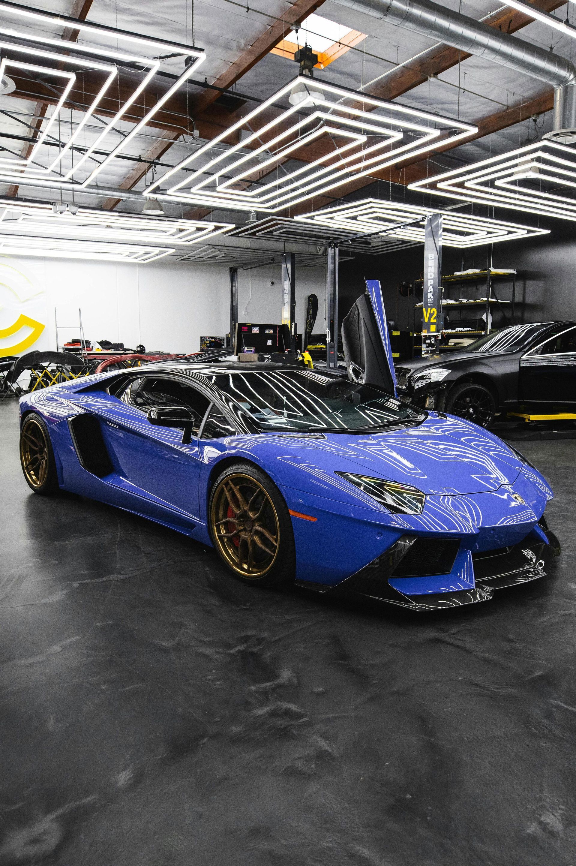 A blue lamborghini aventador is parked in a garage.