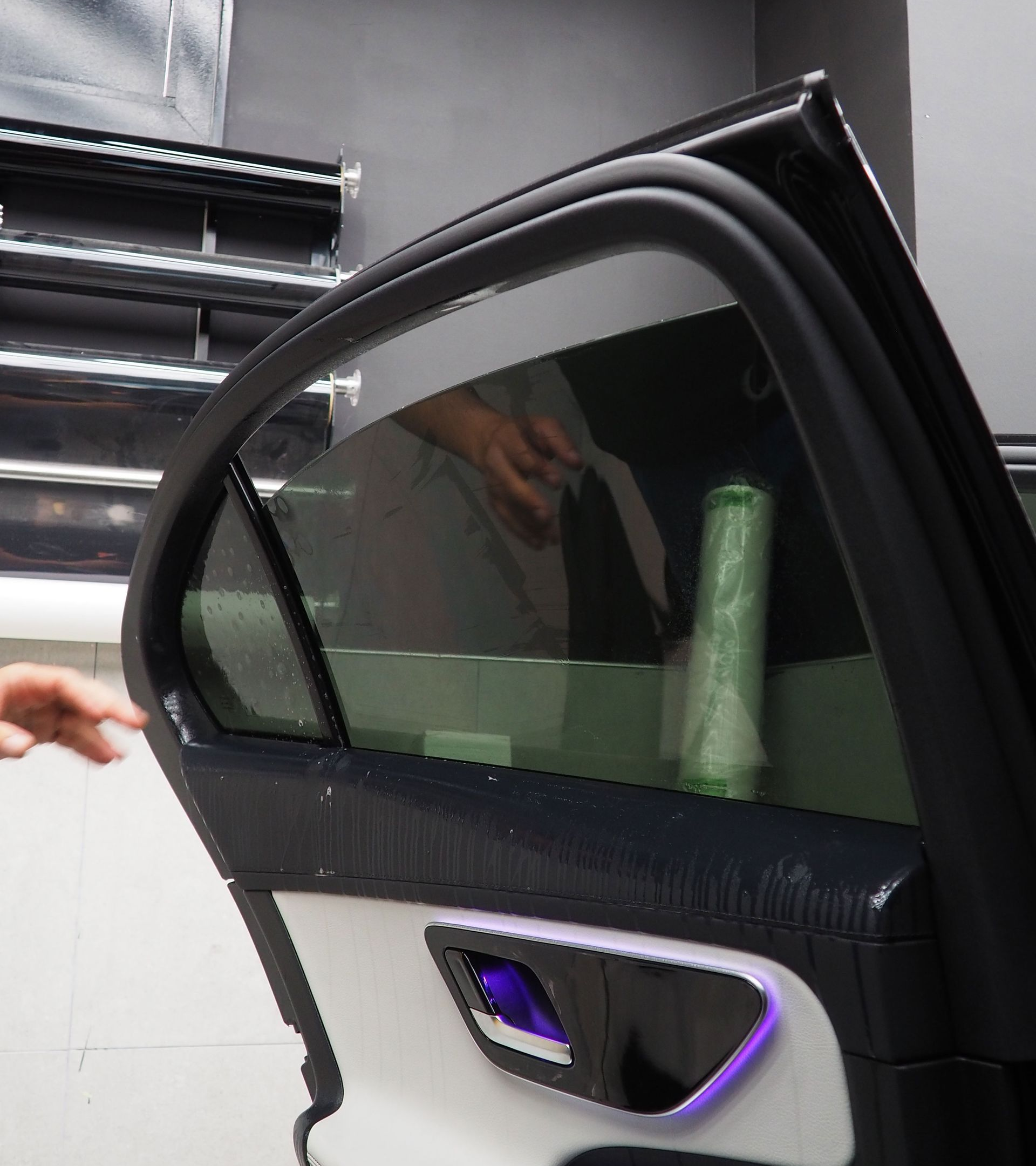 Car door with tinted window being worked on. Interior detail: white and purple trim.