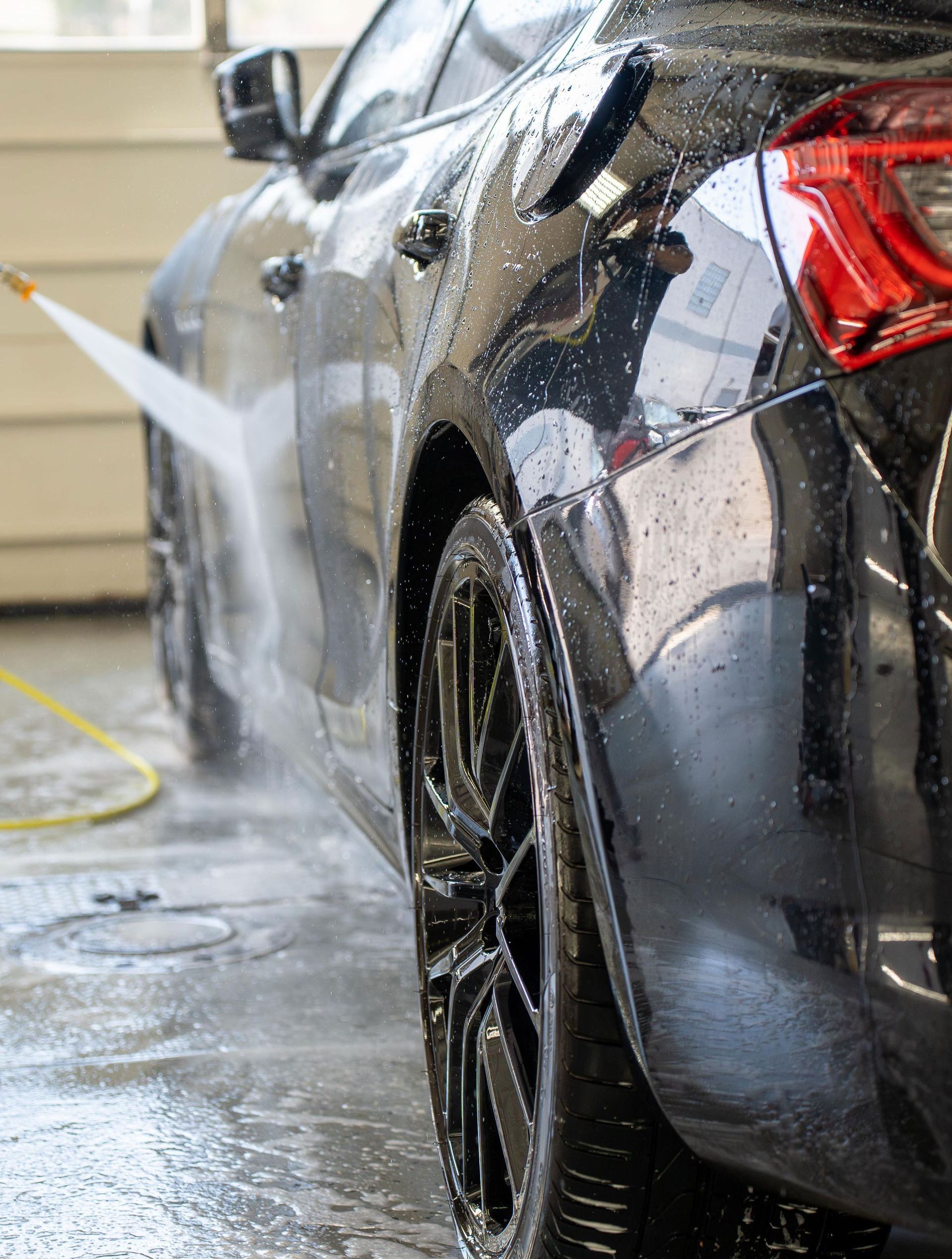 A car is being washed with a high pressure washer.