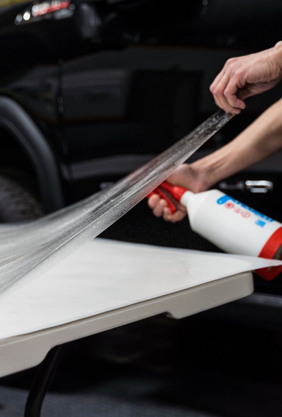 A person is spraying plastic wrap on a table.
