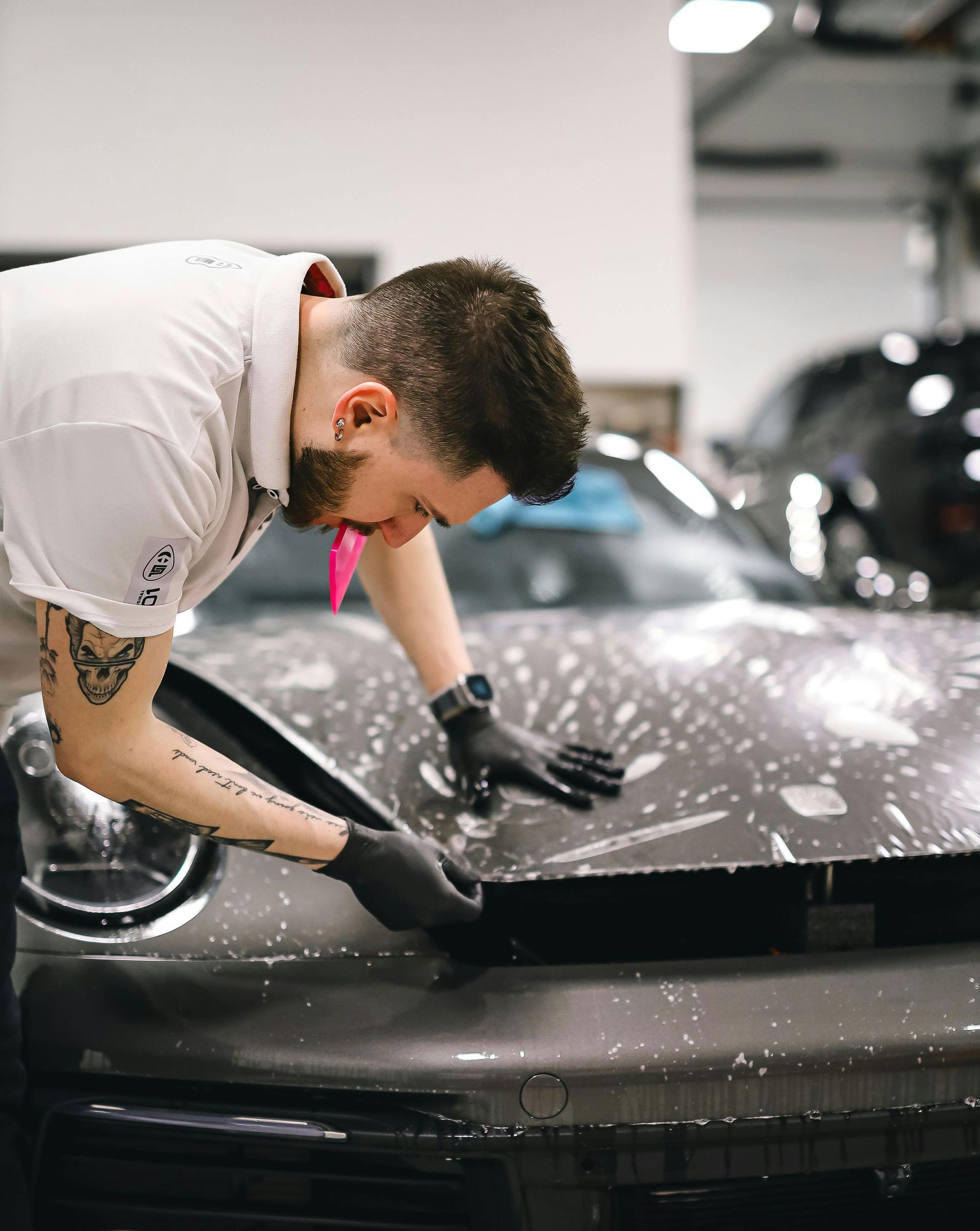 A person is applying a protective film to the hood of a car.
