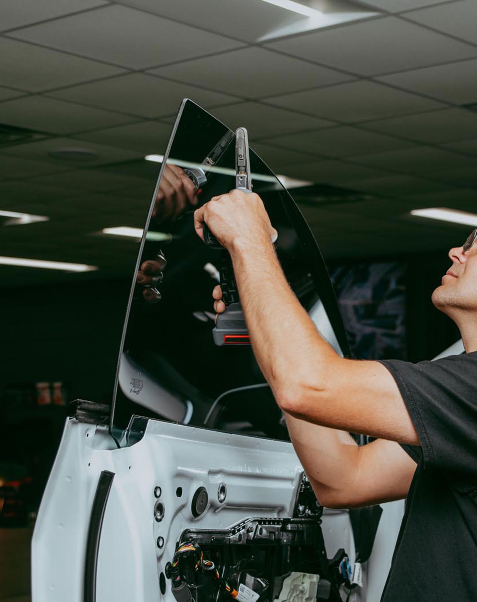 A man is applying window tinting to a car window.