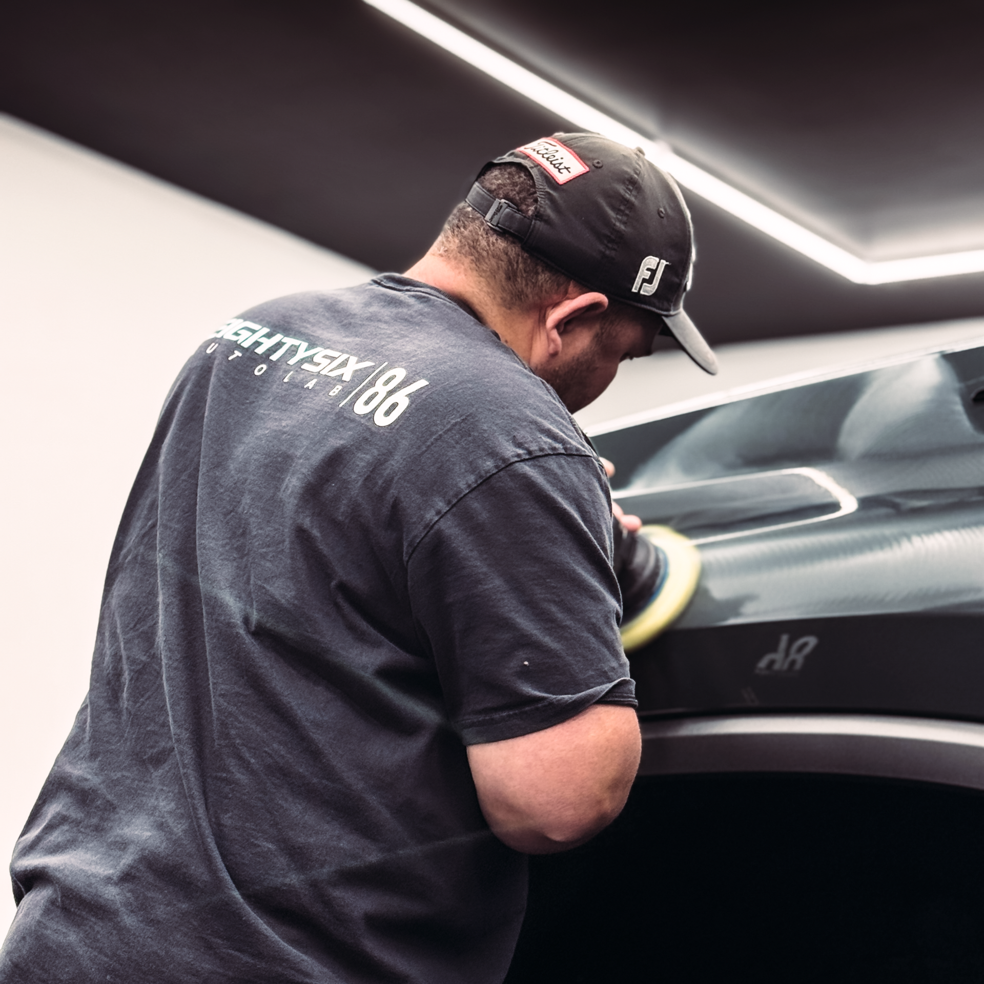 A person is polishing the hood of a car with a machine.