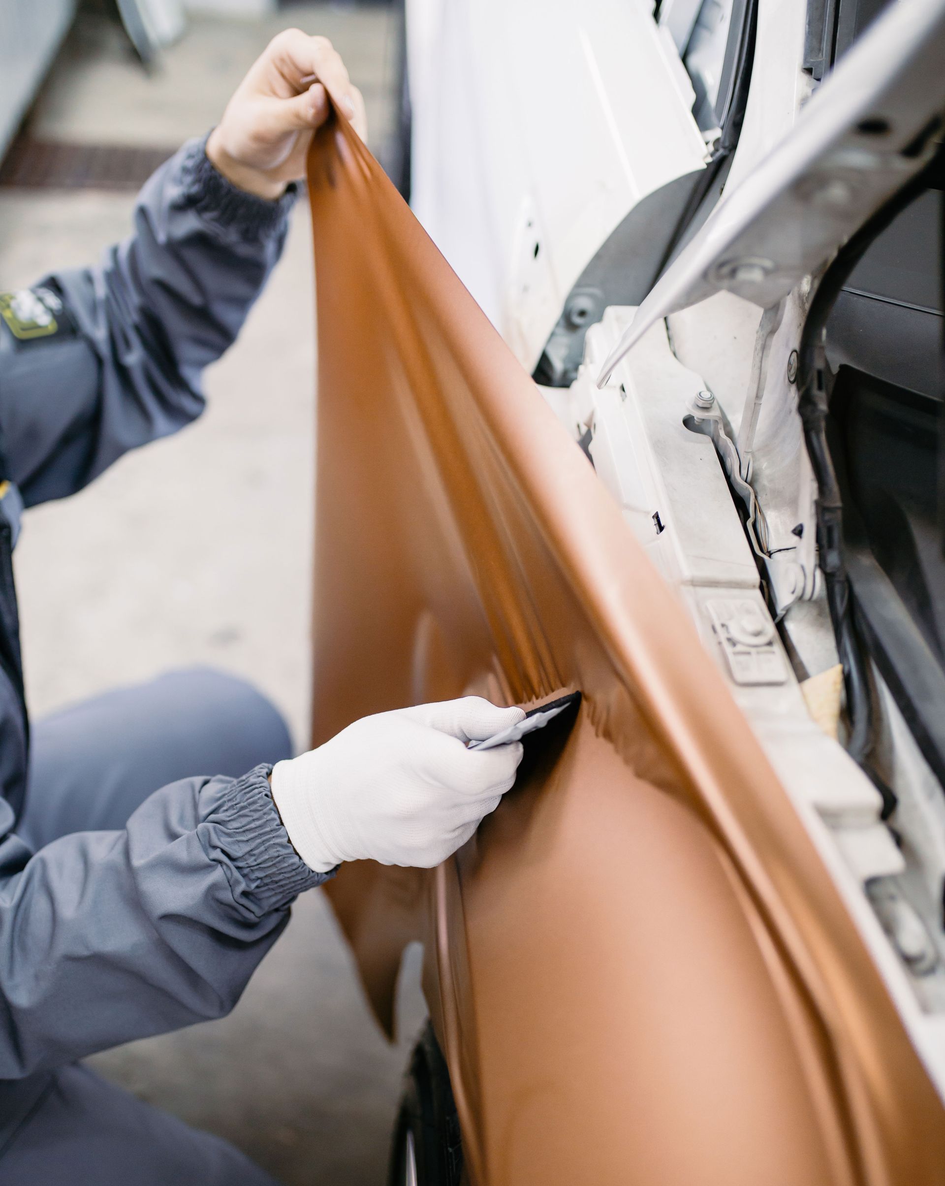 A man is wrapping a car in a brown wrap.