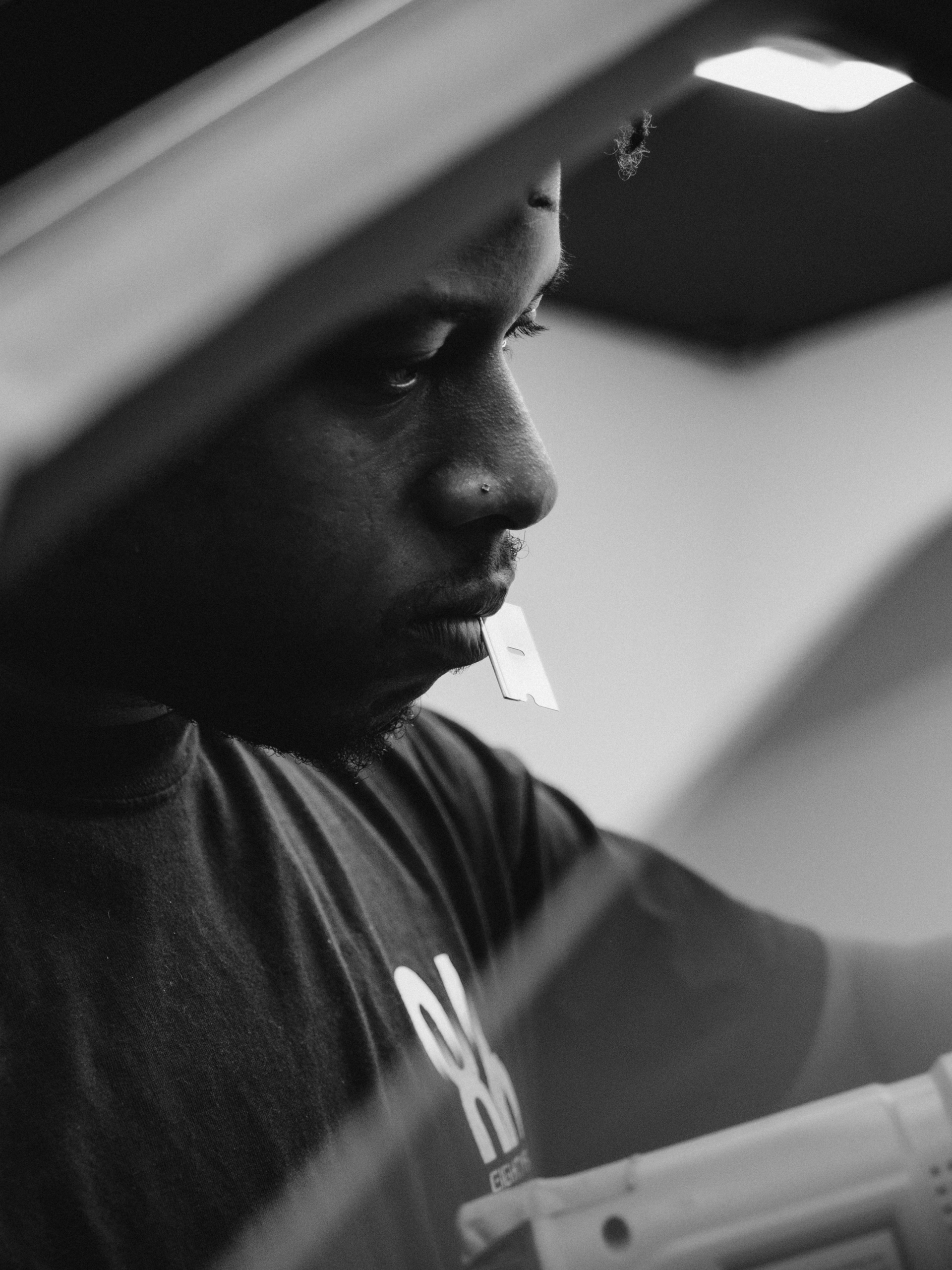Man working, looking down, light source above. Black and white photo.
