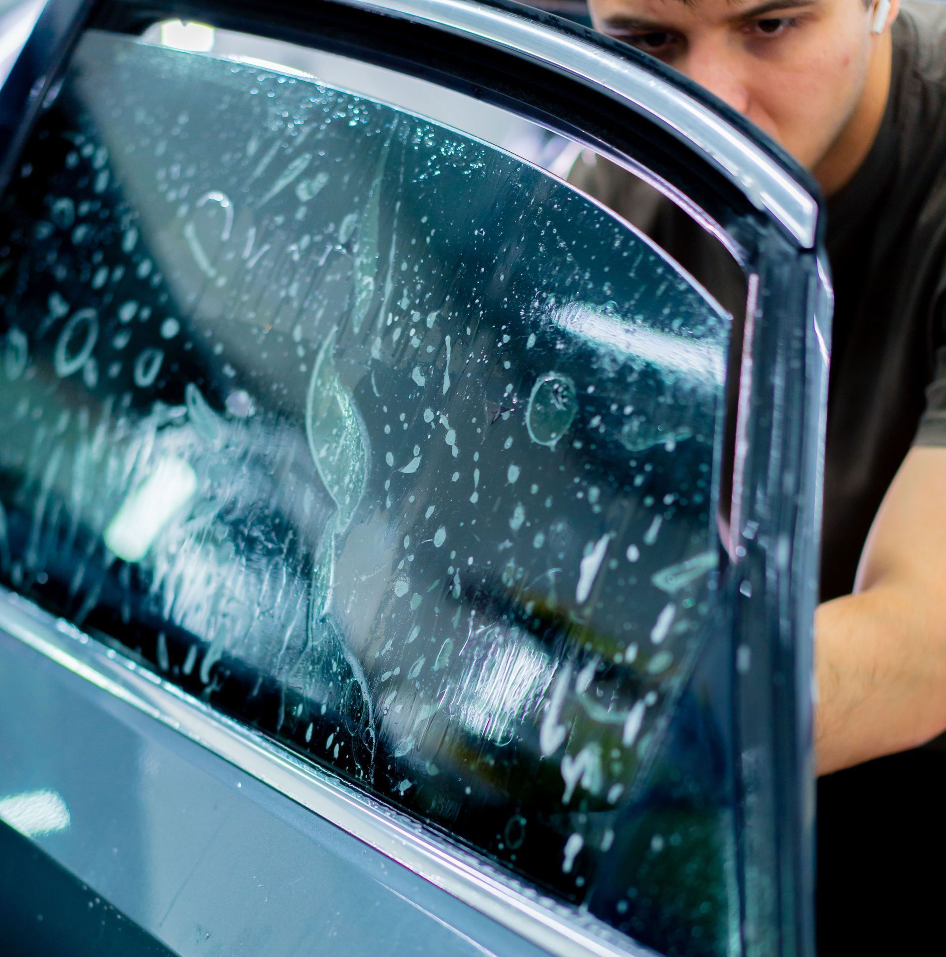 A man is applying window tinting to a car window.