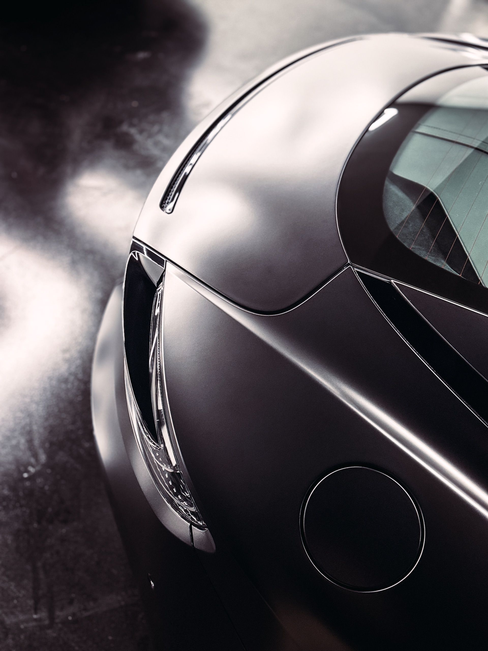 Close-up of a sleek, dark gray car's side, showcasing smooth lines and reflective surface.