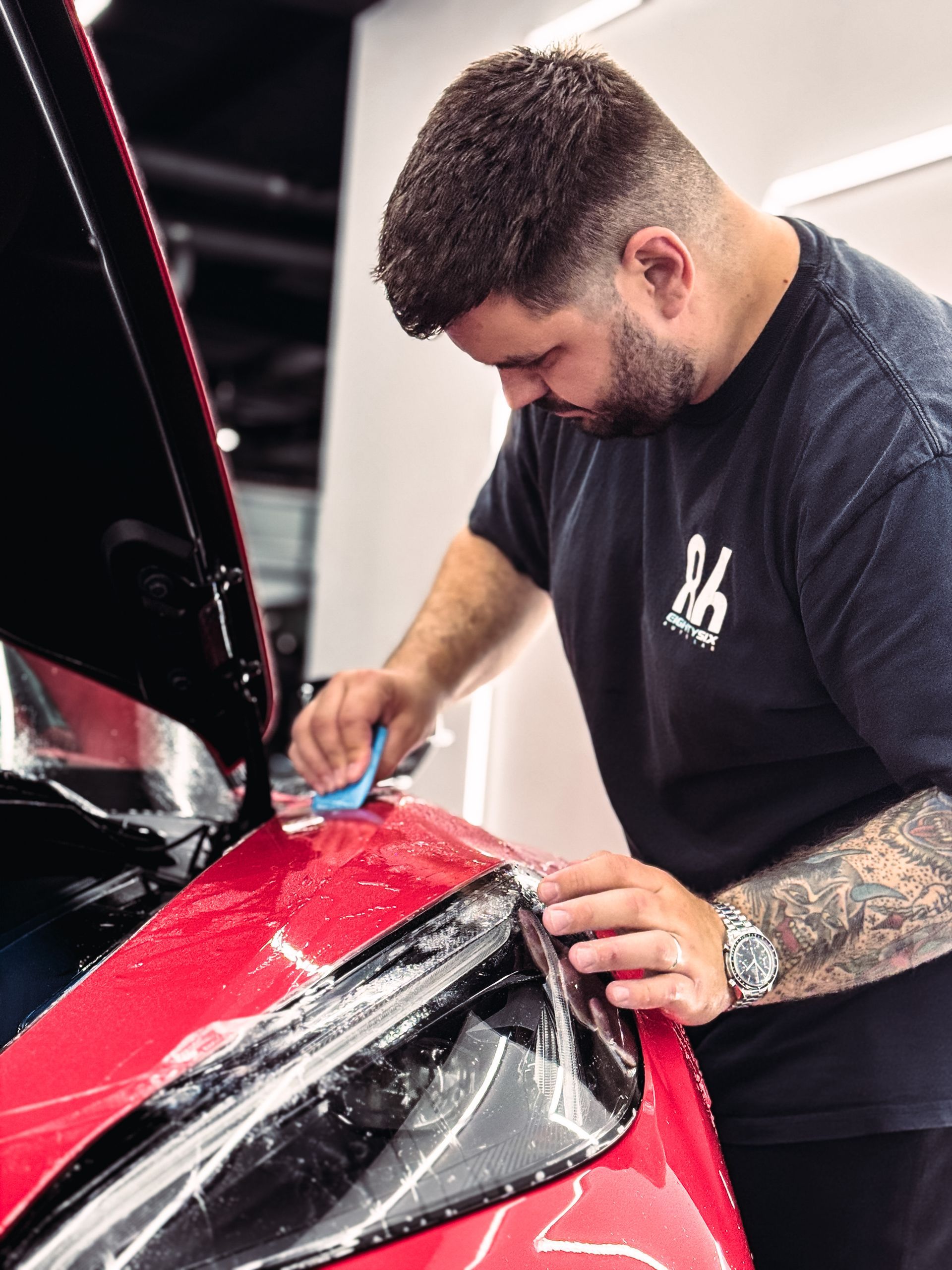 A person is polishing a black car with a sponge.