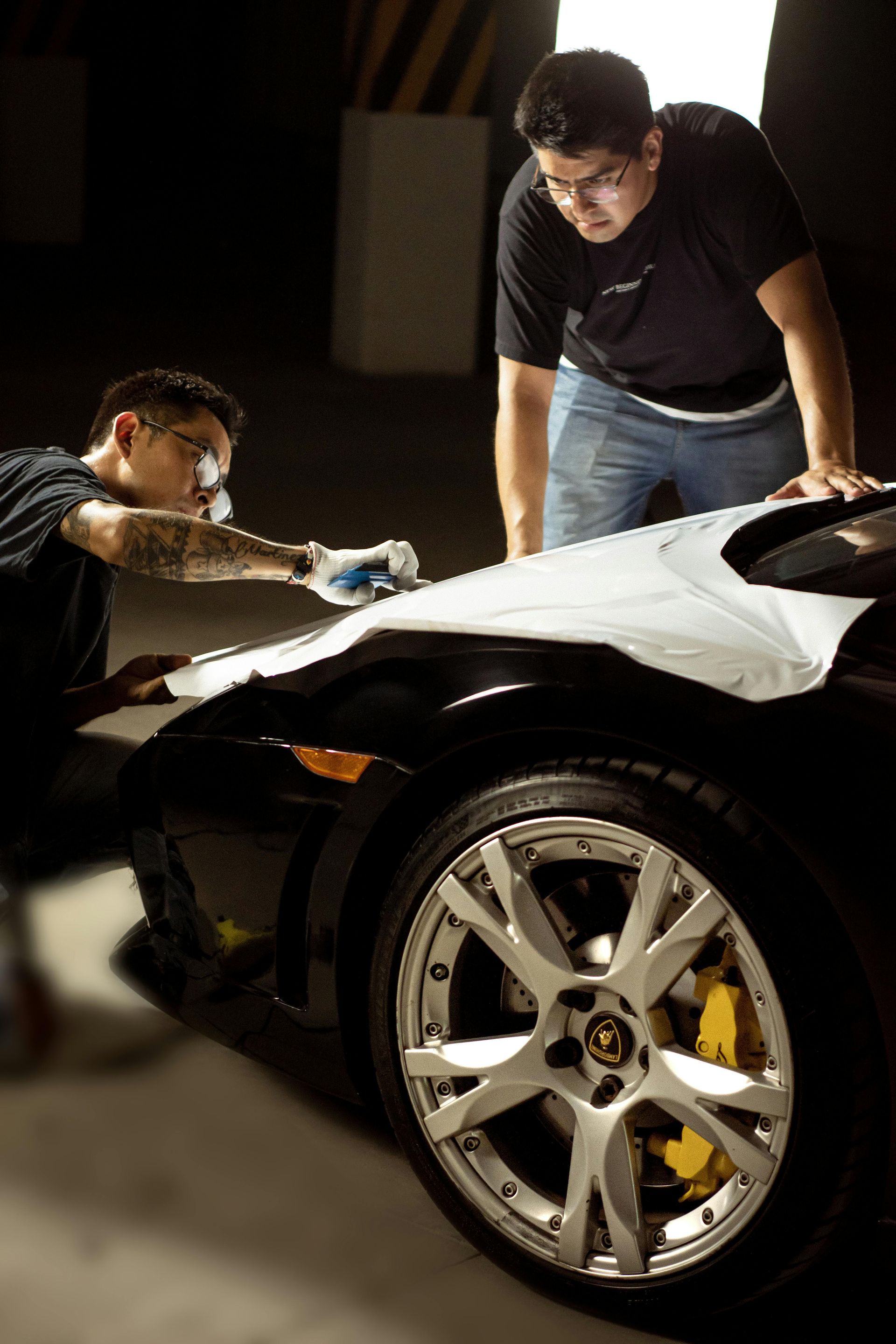 Two men are working on a car in a garage.