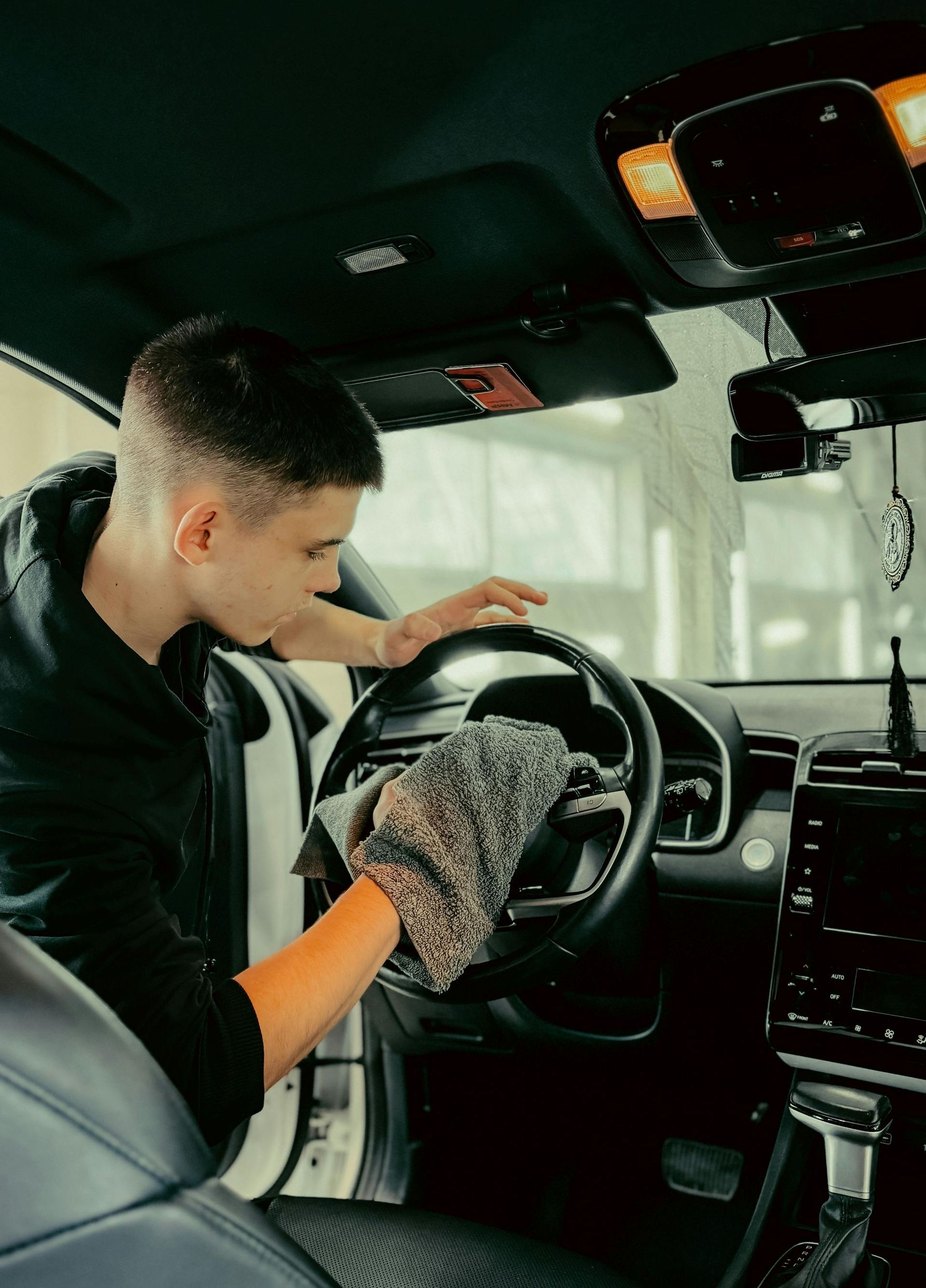 A man is polishing the headlight of a car in a garage.