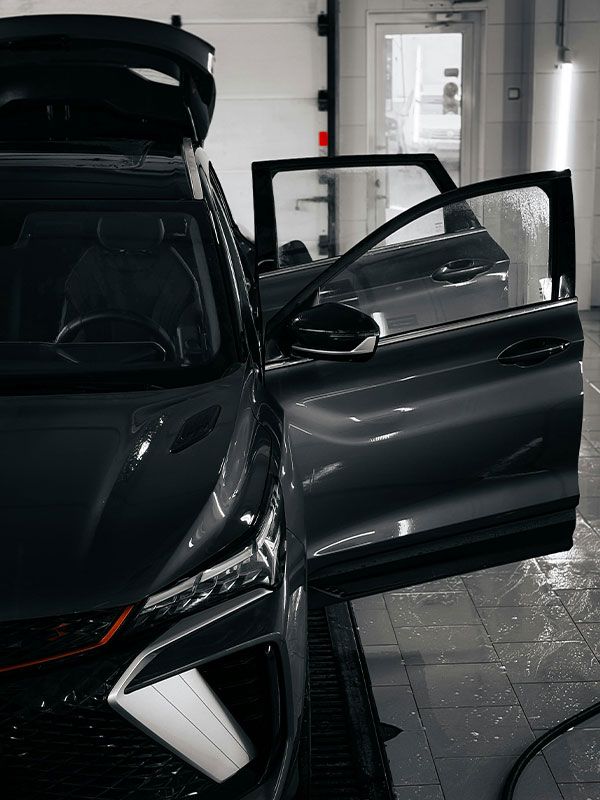 A car is covered in plastic wrap in a garage.