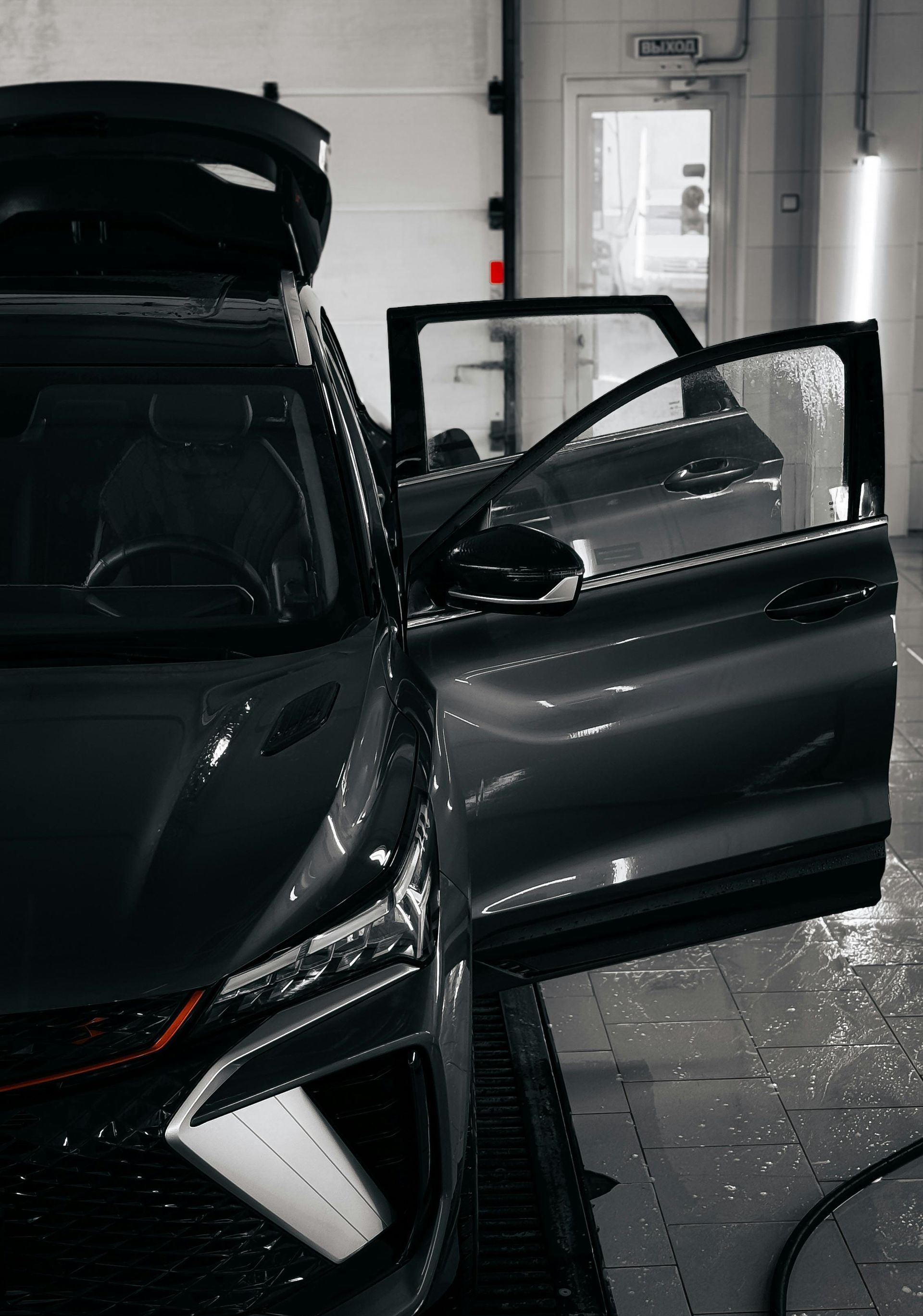 A car is being washed in a garage with its doors open.