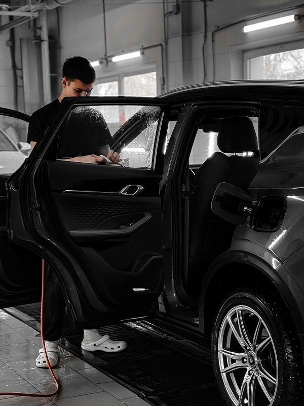 A man is cleaning the inside of a car in a garage.