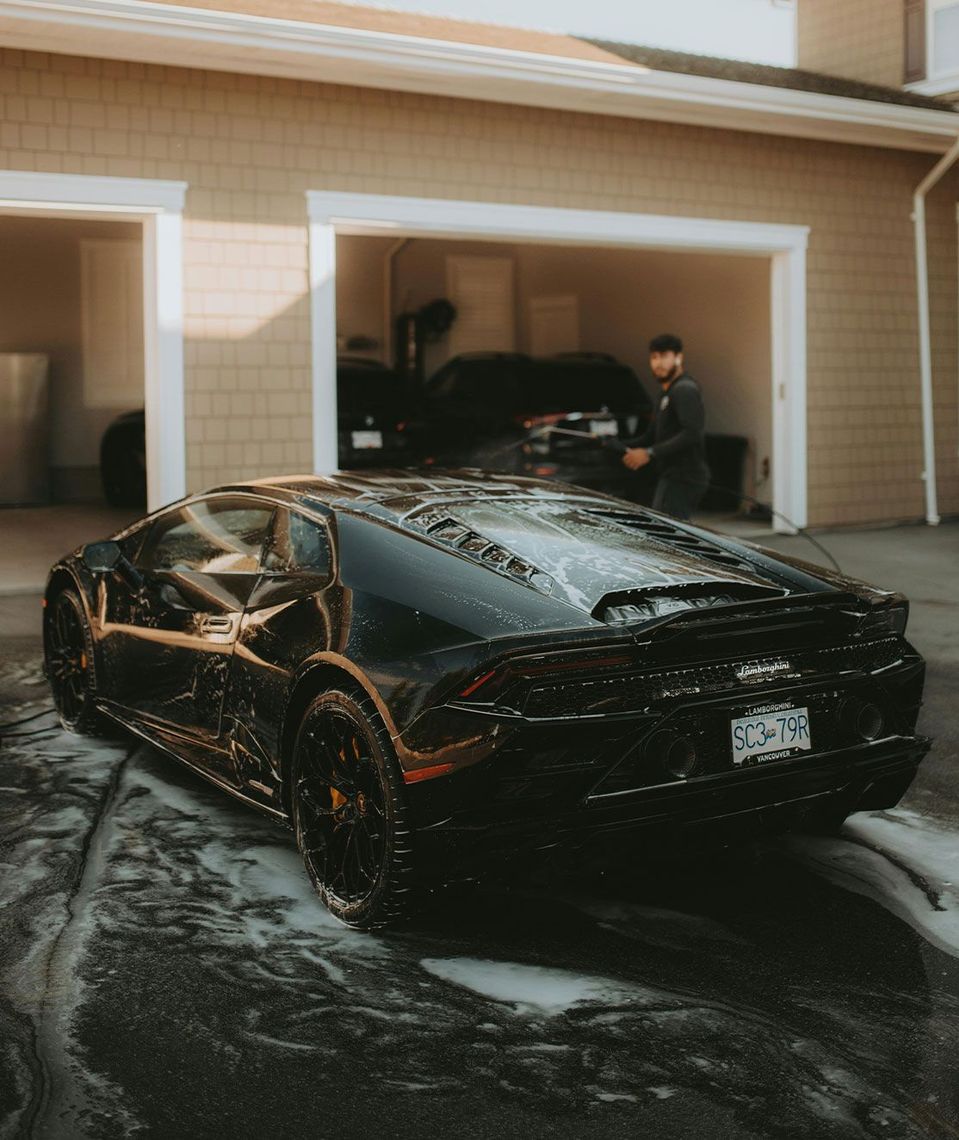 A black sports car is parked in front of a garage.