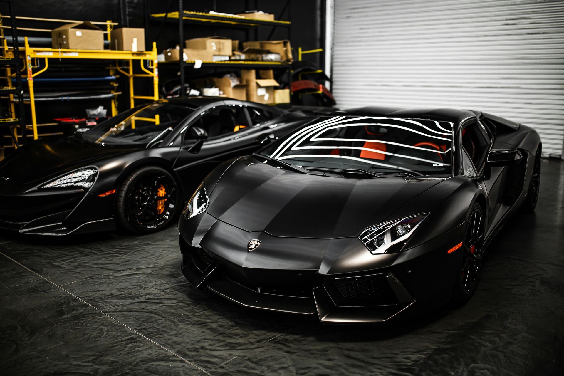 Two black sports cars are parked next to each other in a garage.