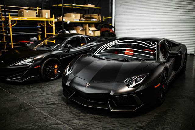 Two black sports cars are parked next to each other in a garage.