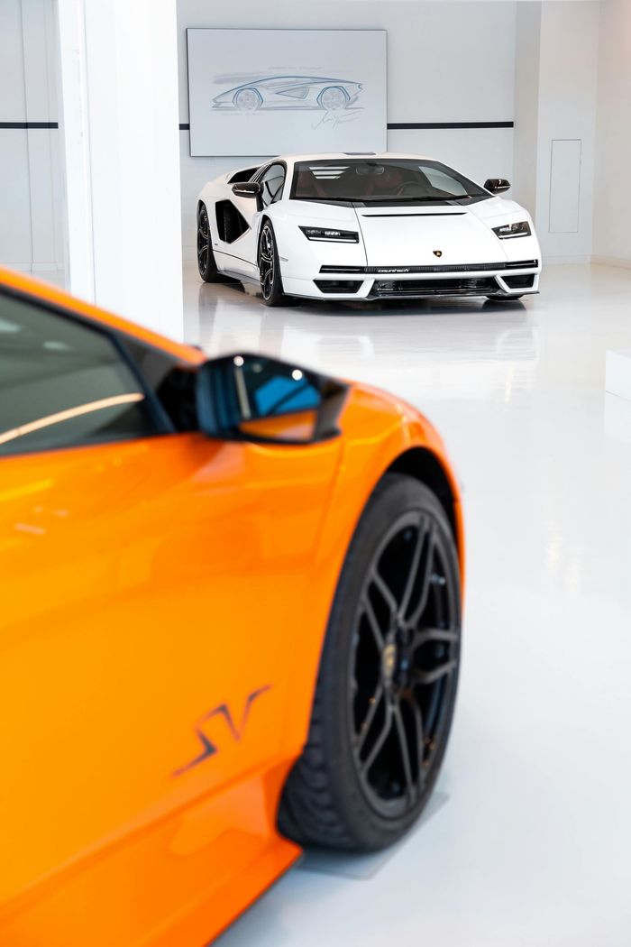 An orange car is parked next to a white car