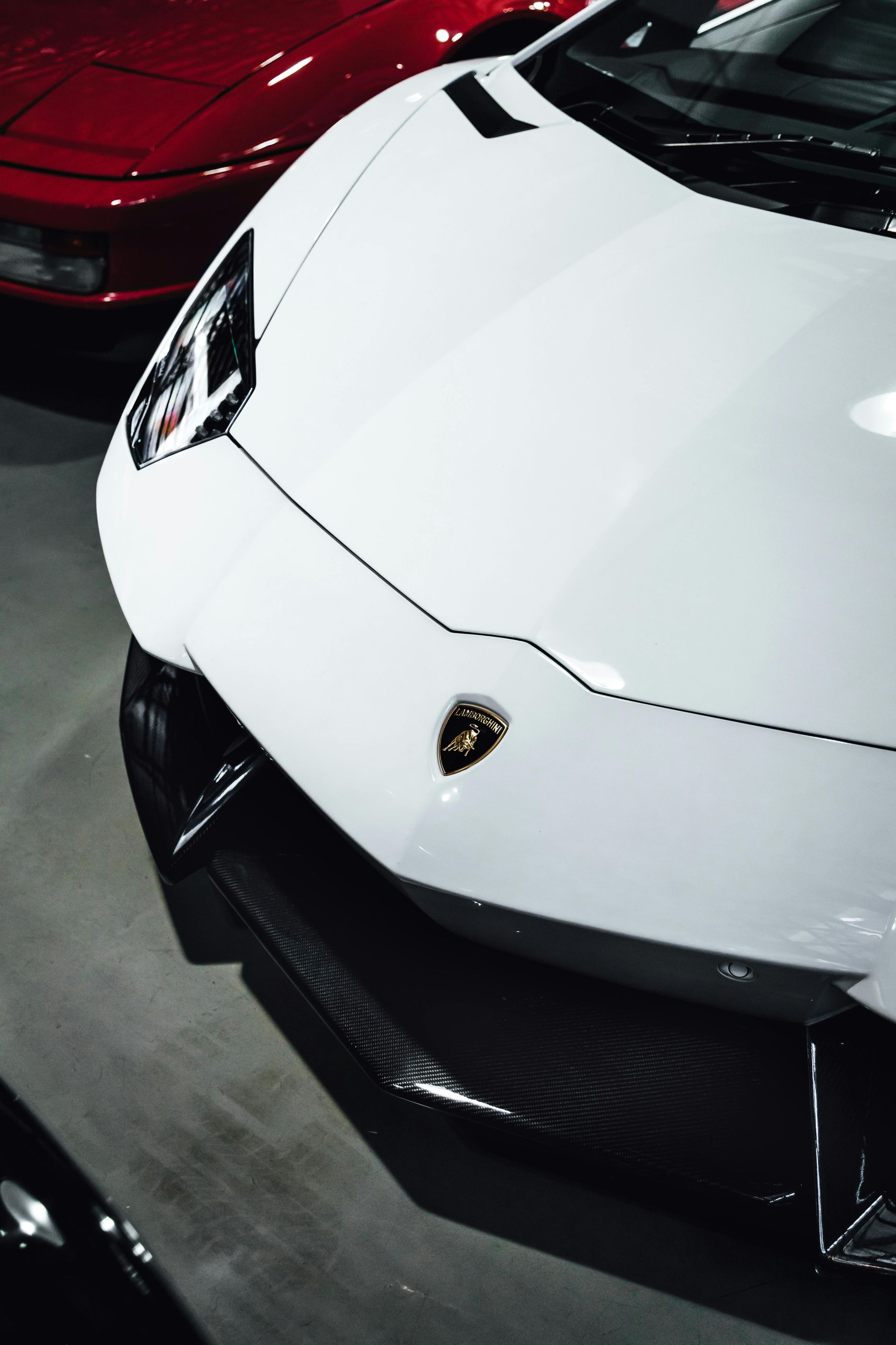 A white lamborghini aventador is parked next to a red car