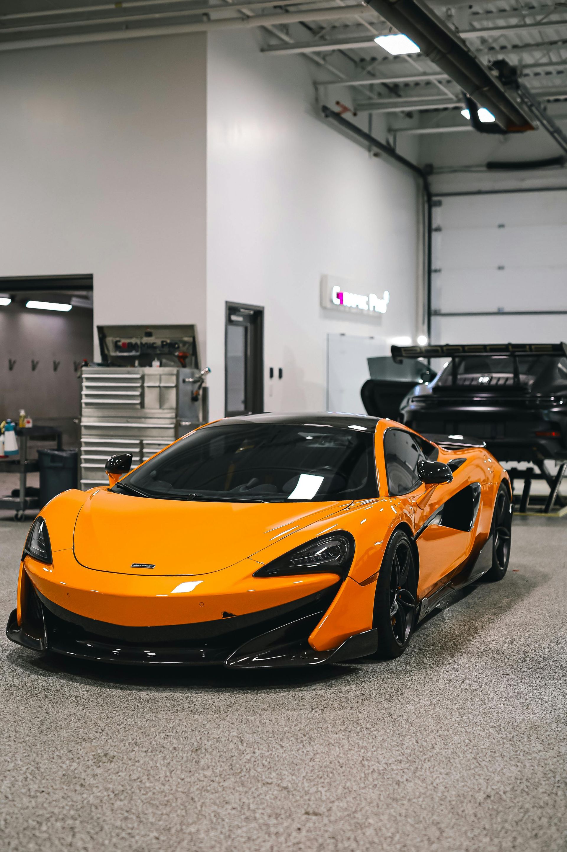 An orange sports car is parked in a garage.
