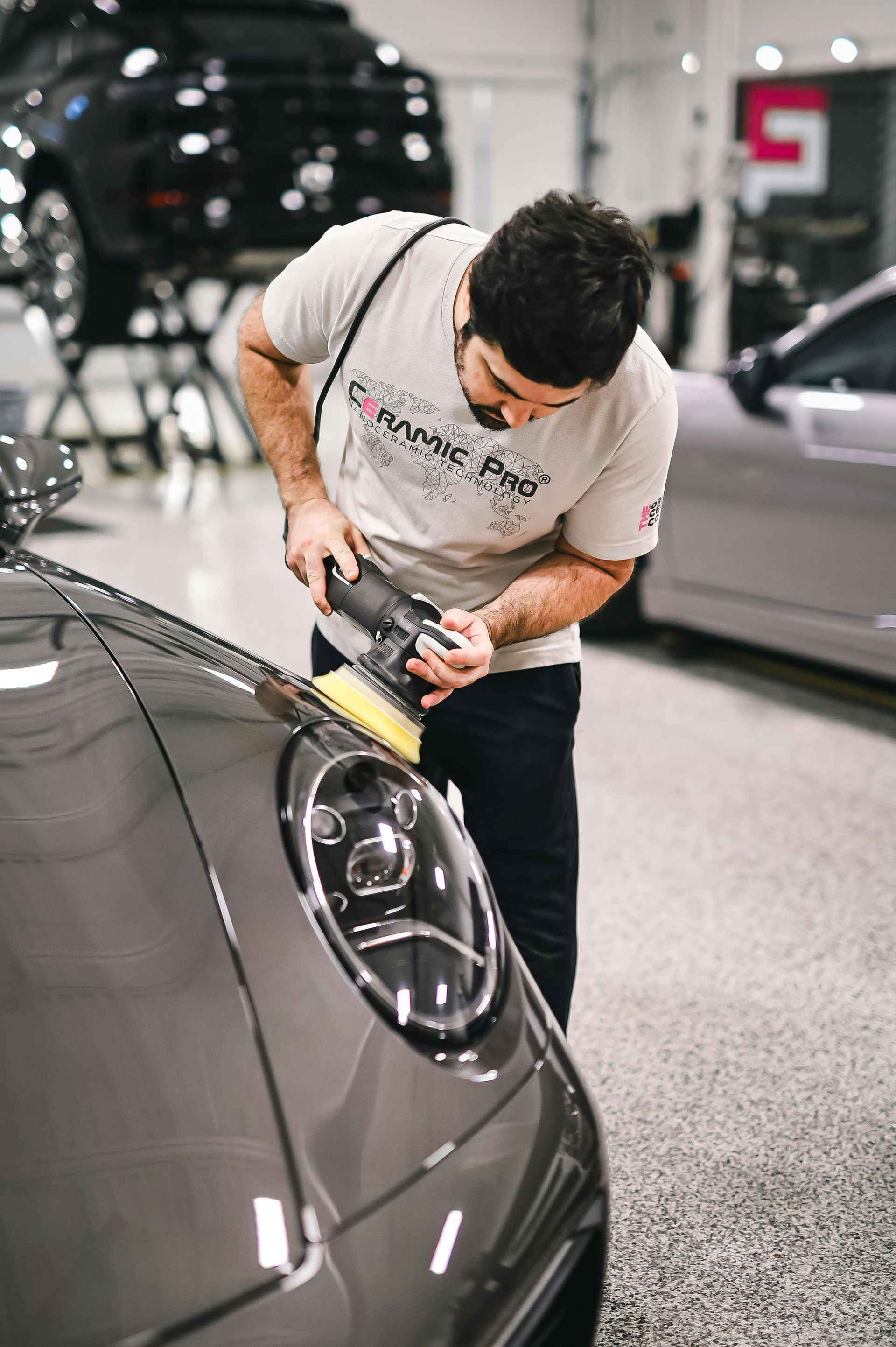 A man is polishing the headlight of a car in a garage.