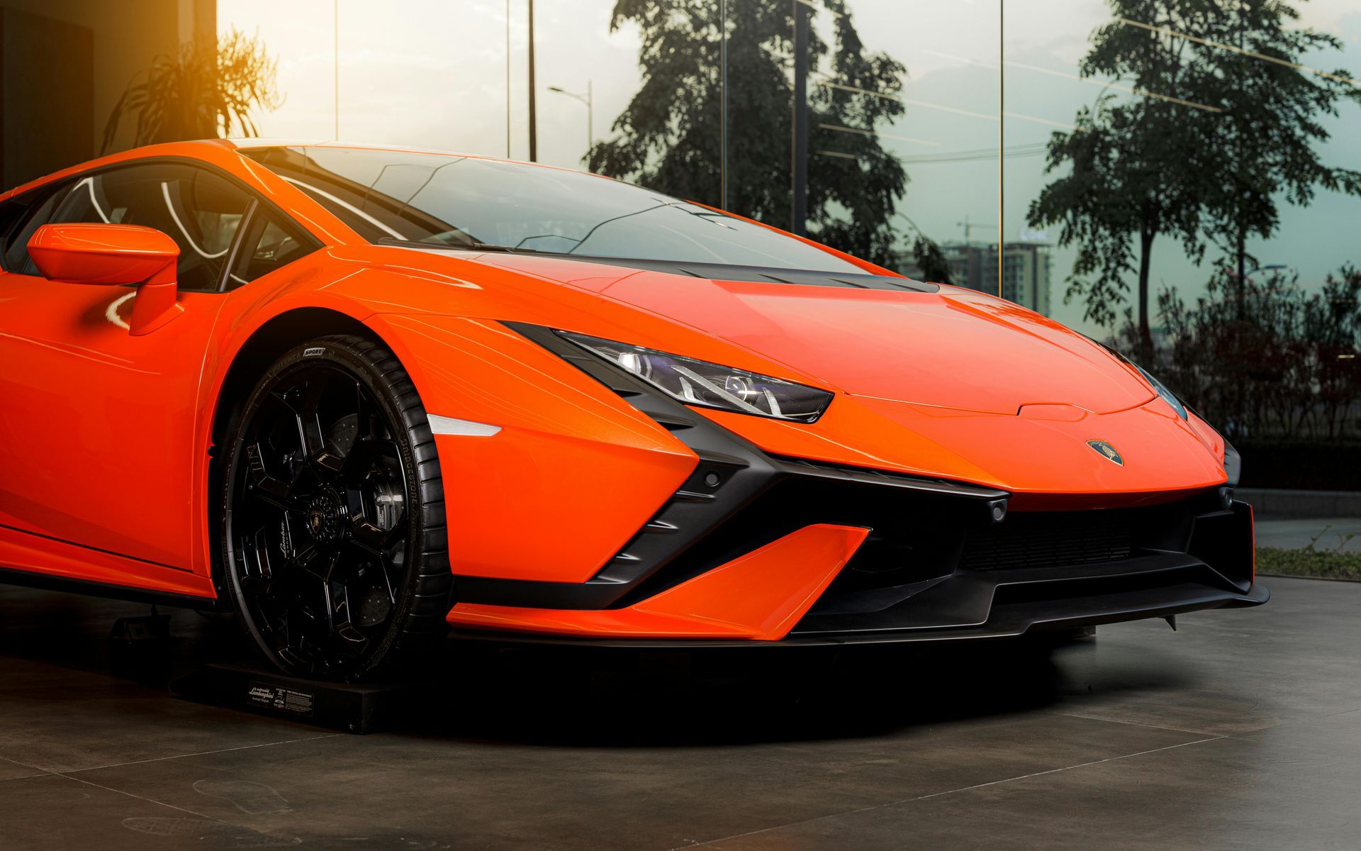 An orange lamborghini huracan is parked in front of a building.