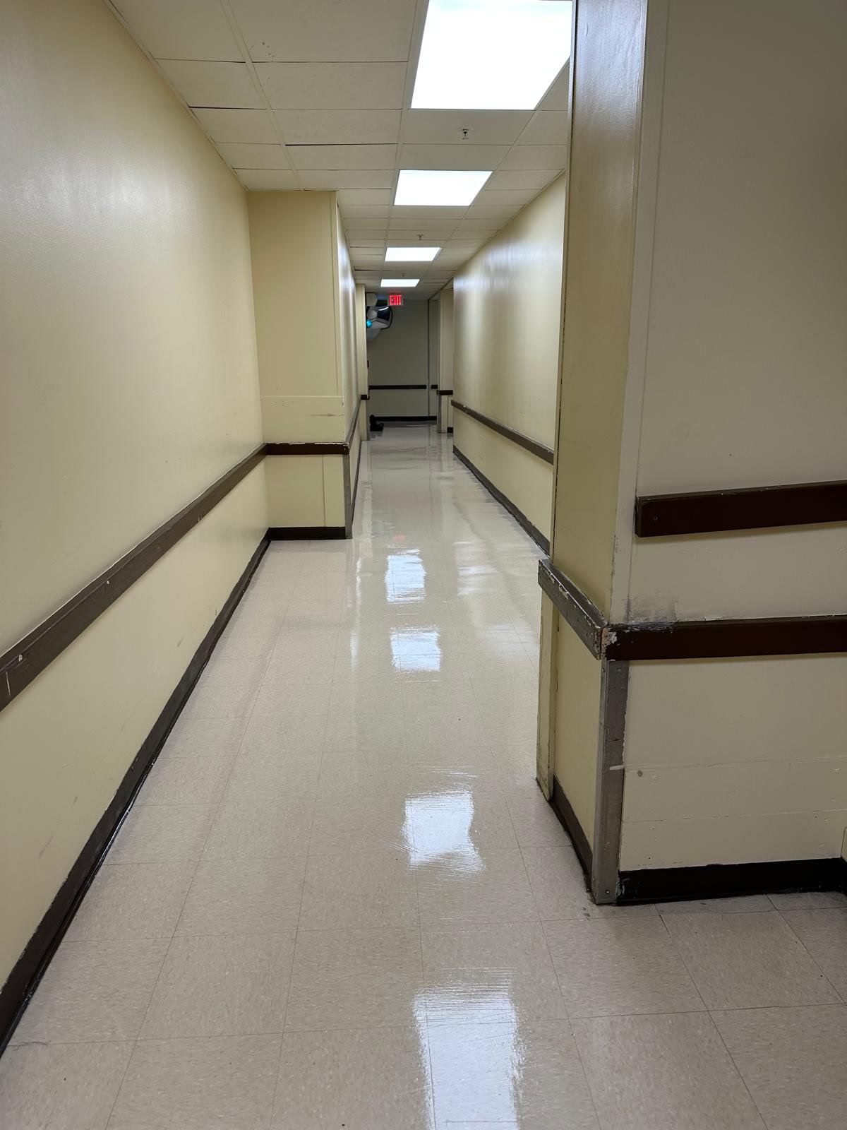 Long, empty beige hallway with glossy floors and ceiling lights.