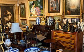 Blue and white porcelain tea set with a vase and cups on a wooden table next to traditional Chinese calligraphy scrolls.