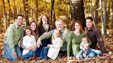 A large family is posing for a picture in the woods.