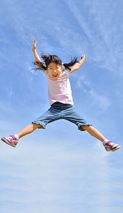 Une petite fille saute en l'air avec les bras en l'air.