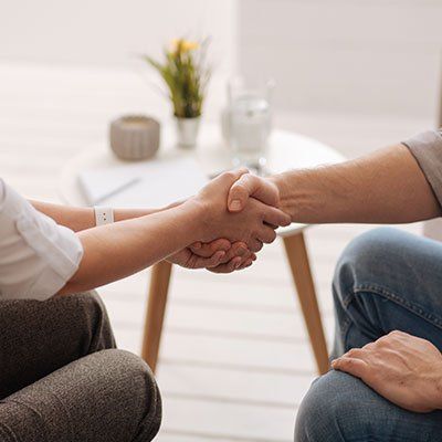 Un homme et une femme se serrent la main alors qu'ils sont assis à une table.