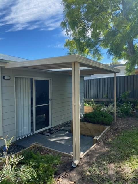 A Metal Awning Oven A Paved Garden From Lil' Shelters Done Right— Kimick Roofing Solutions In Wyong, NSW