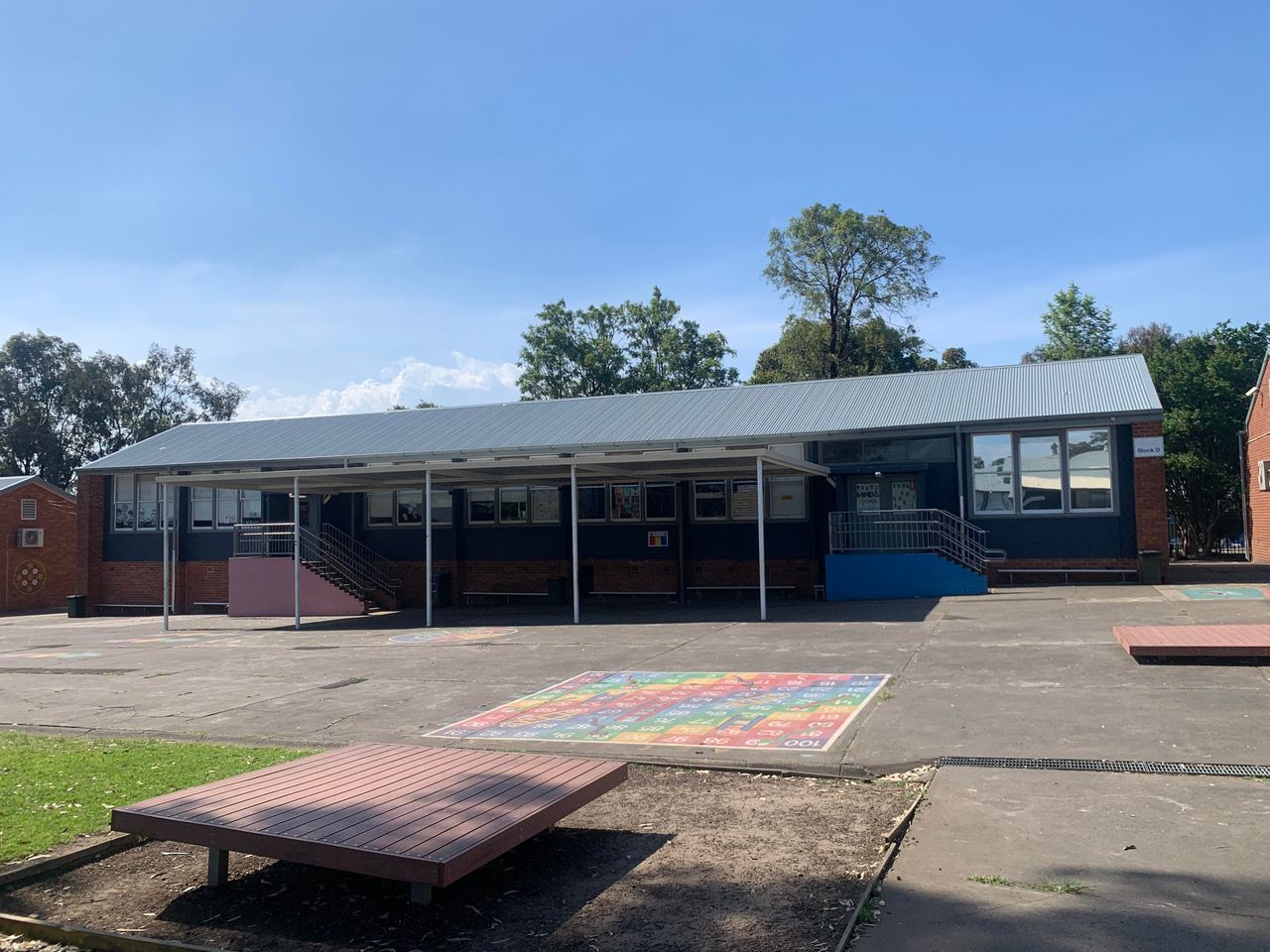 A Large Building Under Construction With A Blue Fence Around It — Kimick Roofing Solutions In Wyong, NSW
