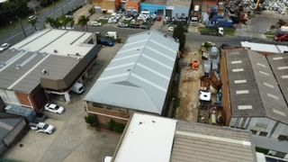 An aerial view of a warehouse with a lot of cars parked in front of it.
