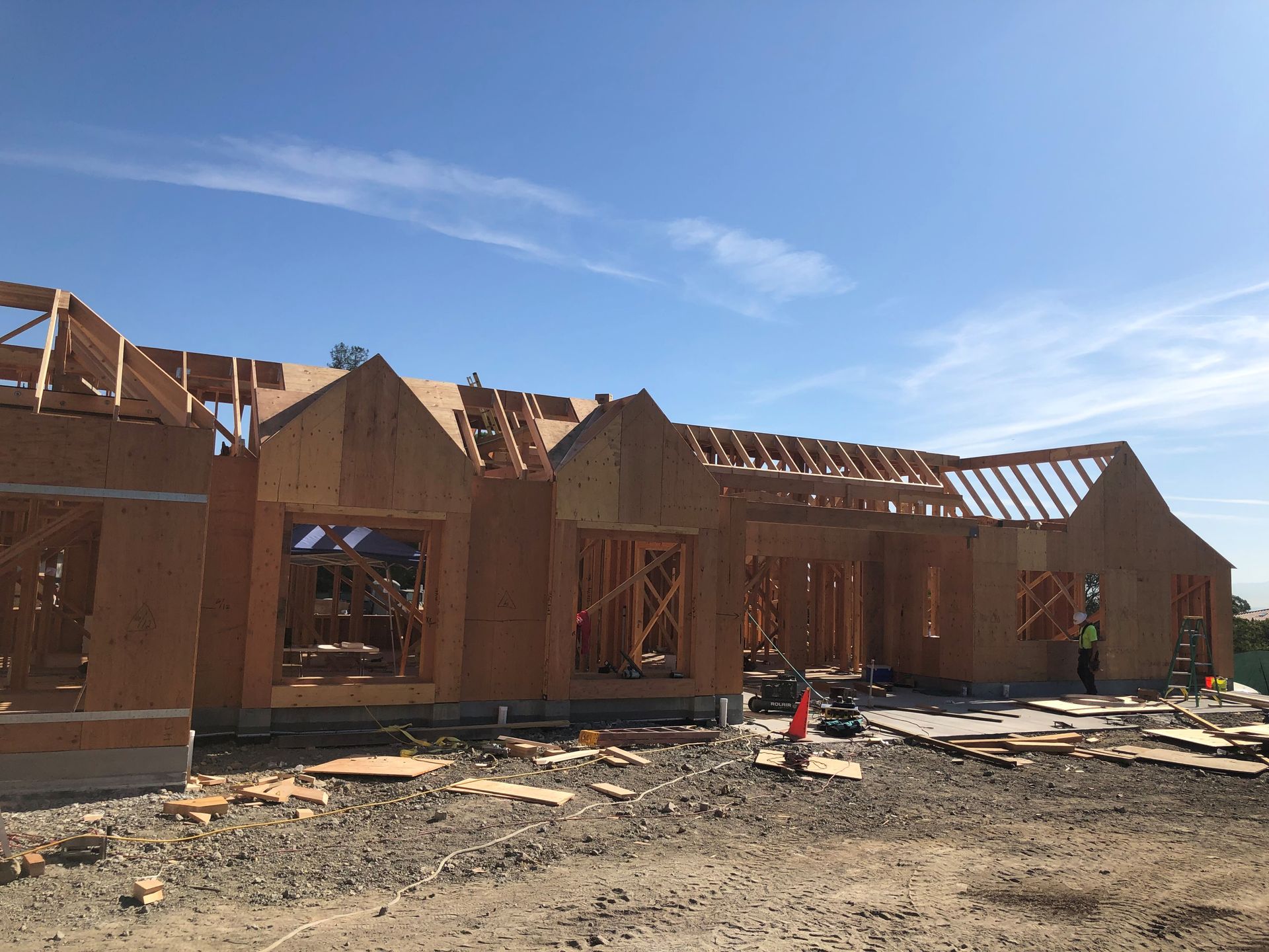 A large house is being built in the middle of a dirt field.