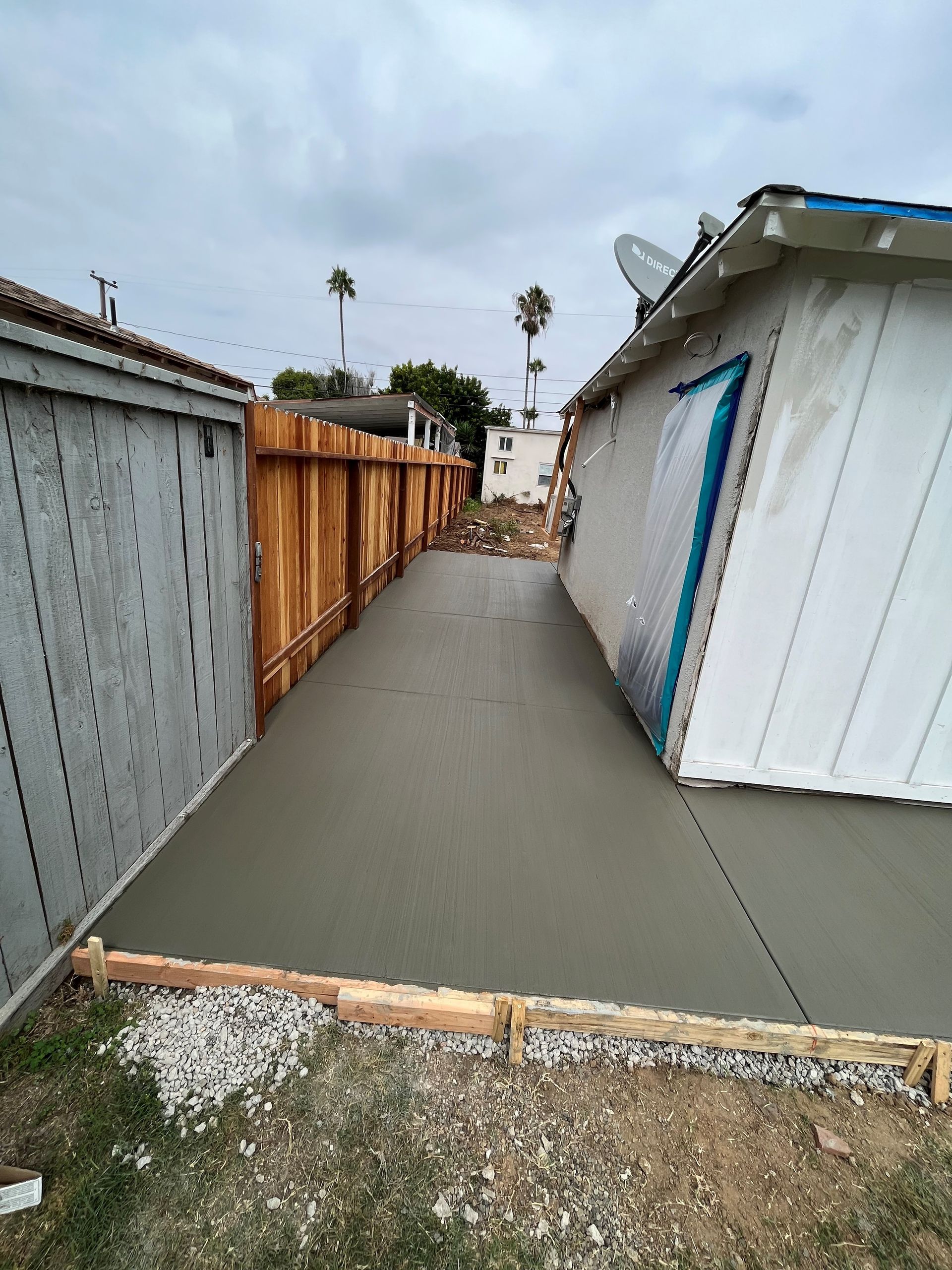 A concrete driveway is being built next to a house.