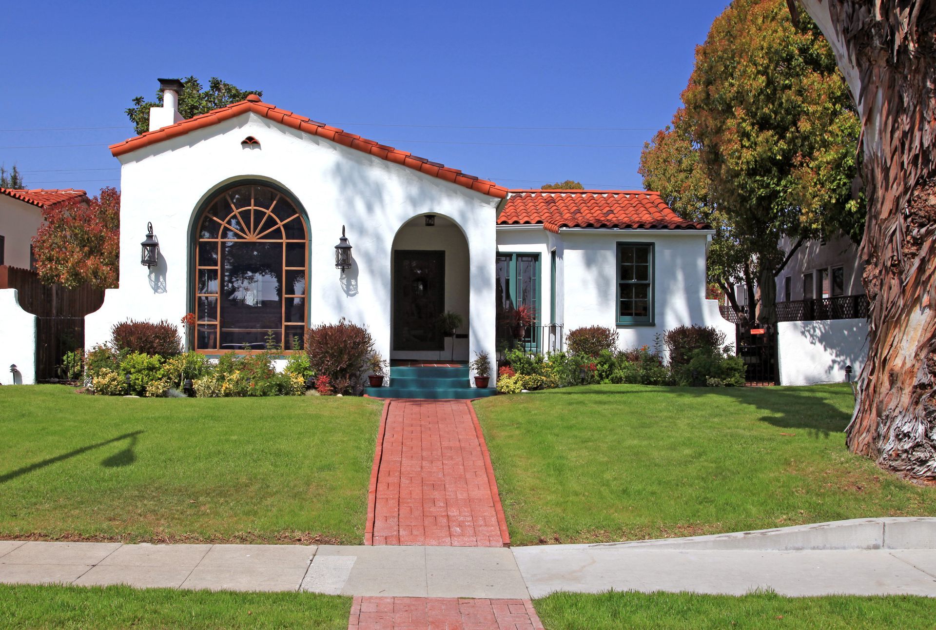 A white house with a red tile roof and a brick walkway