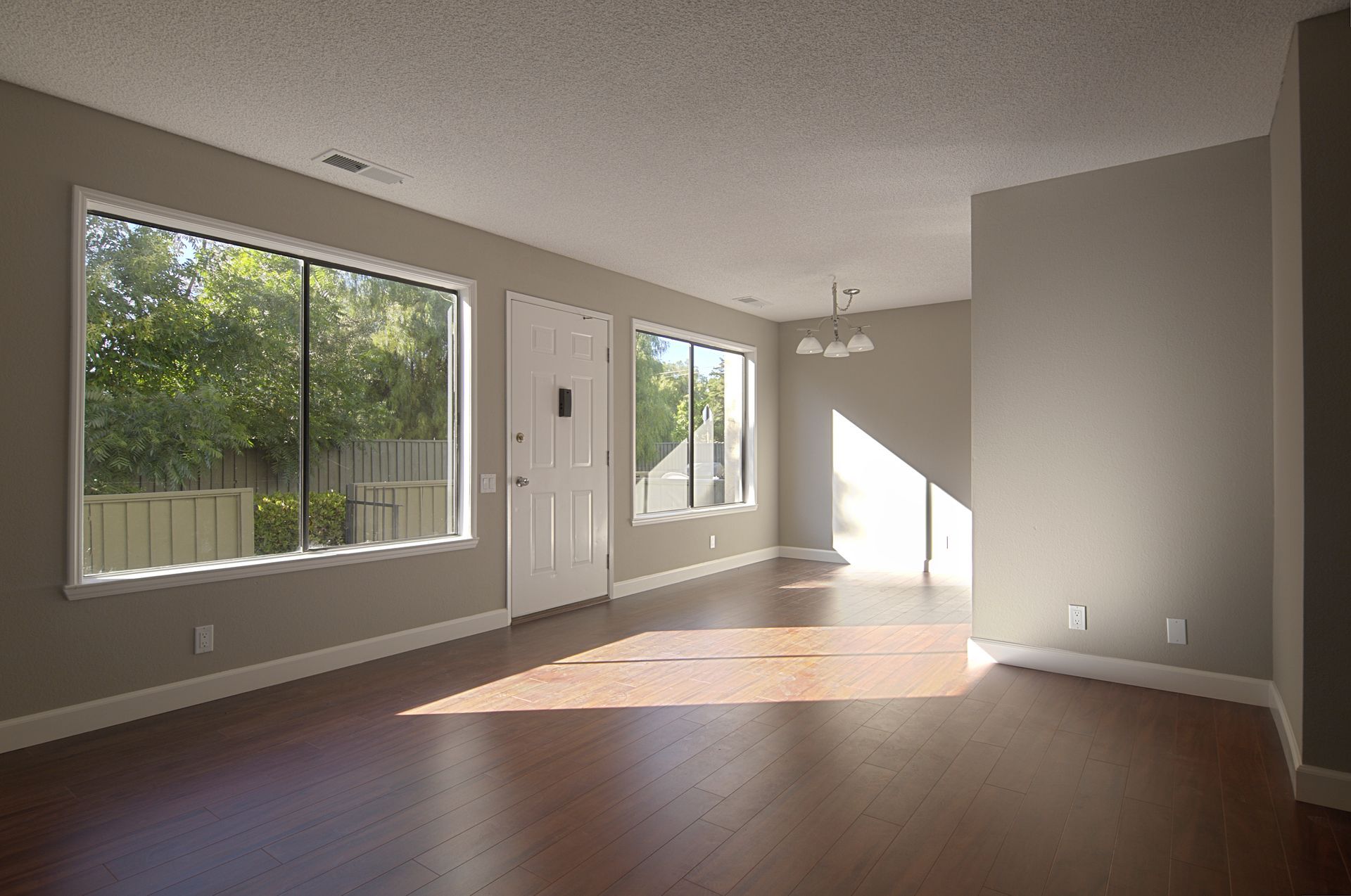 An empty living room with hardwood floors and lots of windows.