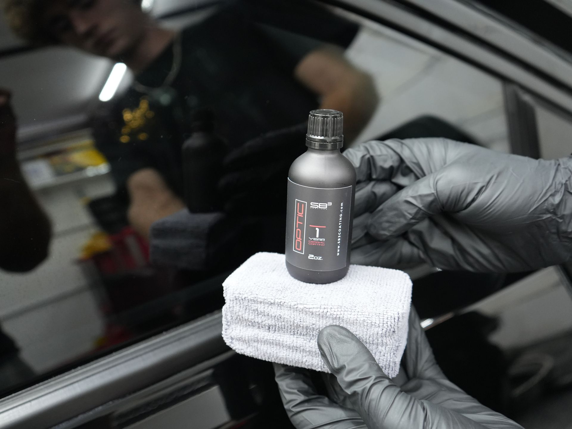 a person wearing gloves is holding a bottle that says optic on it