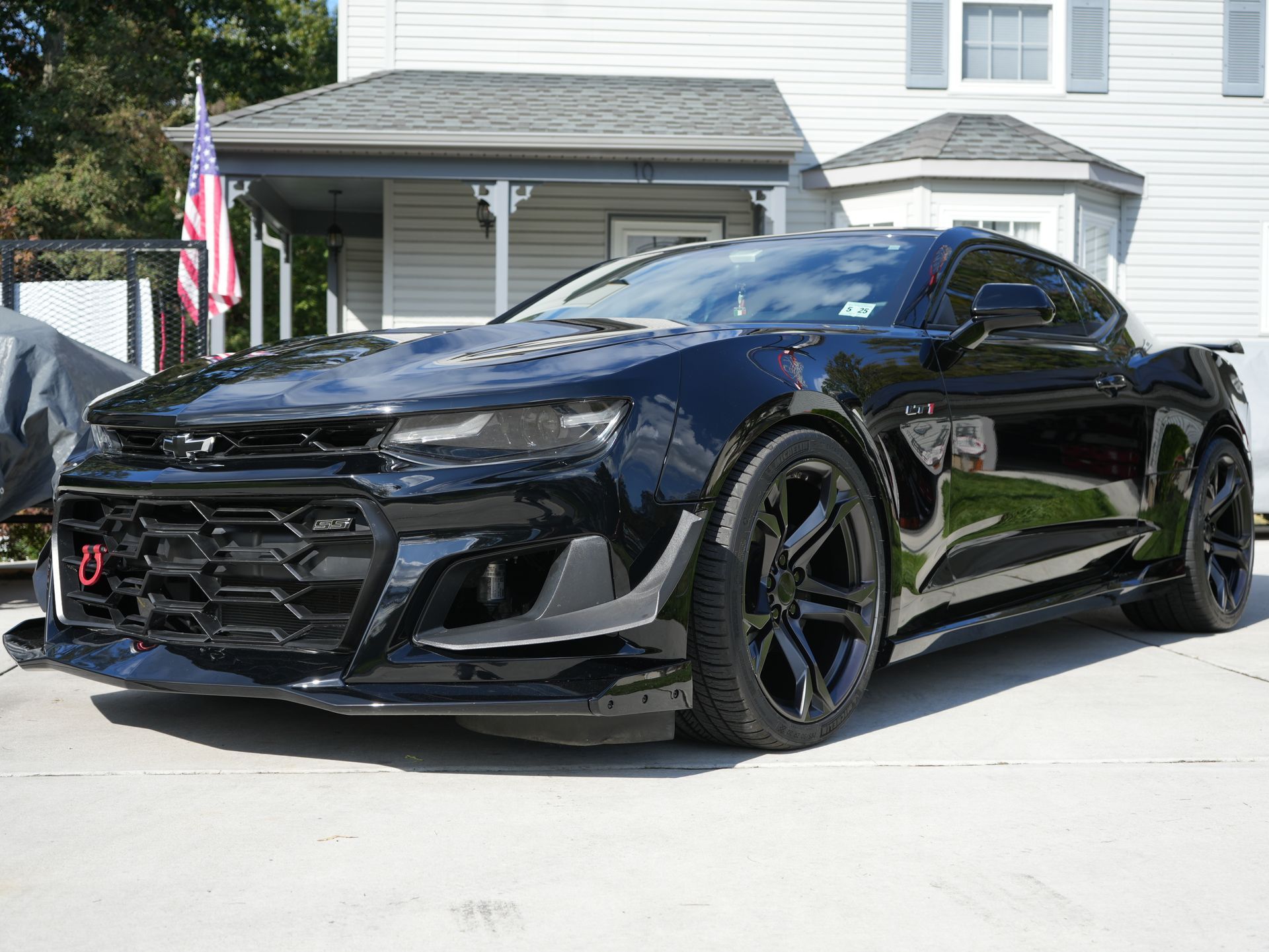 a black chevrolet camaro gt is parked in front of a house