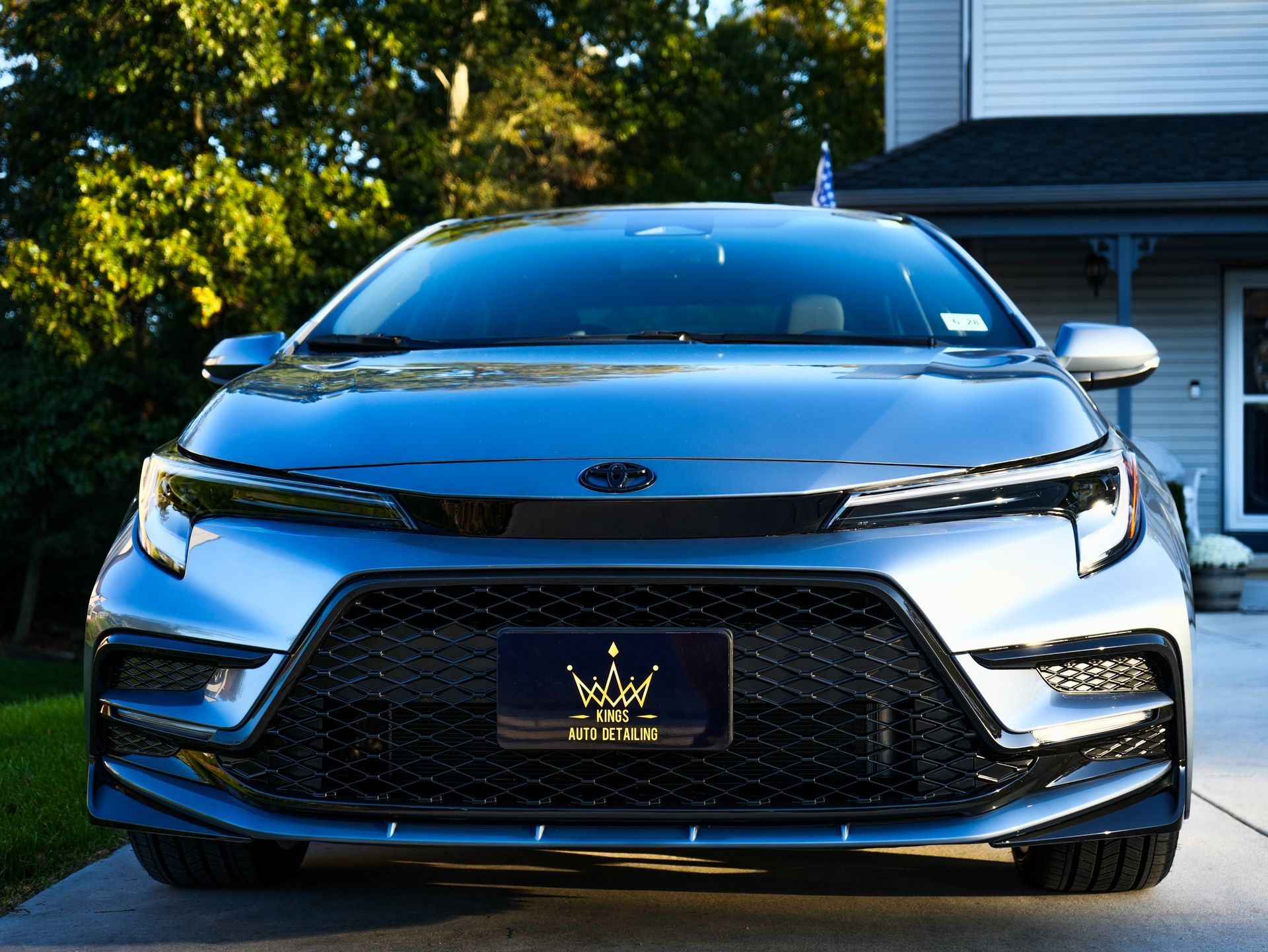 A person is washing the windshield of a blue car