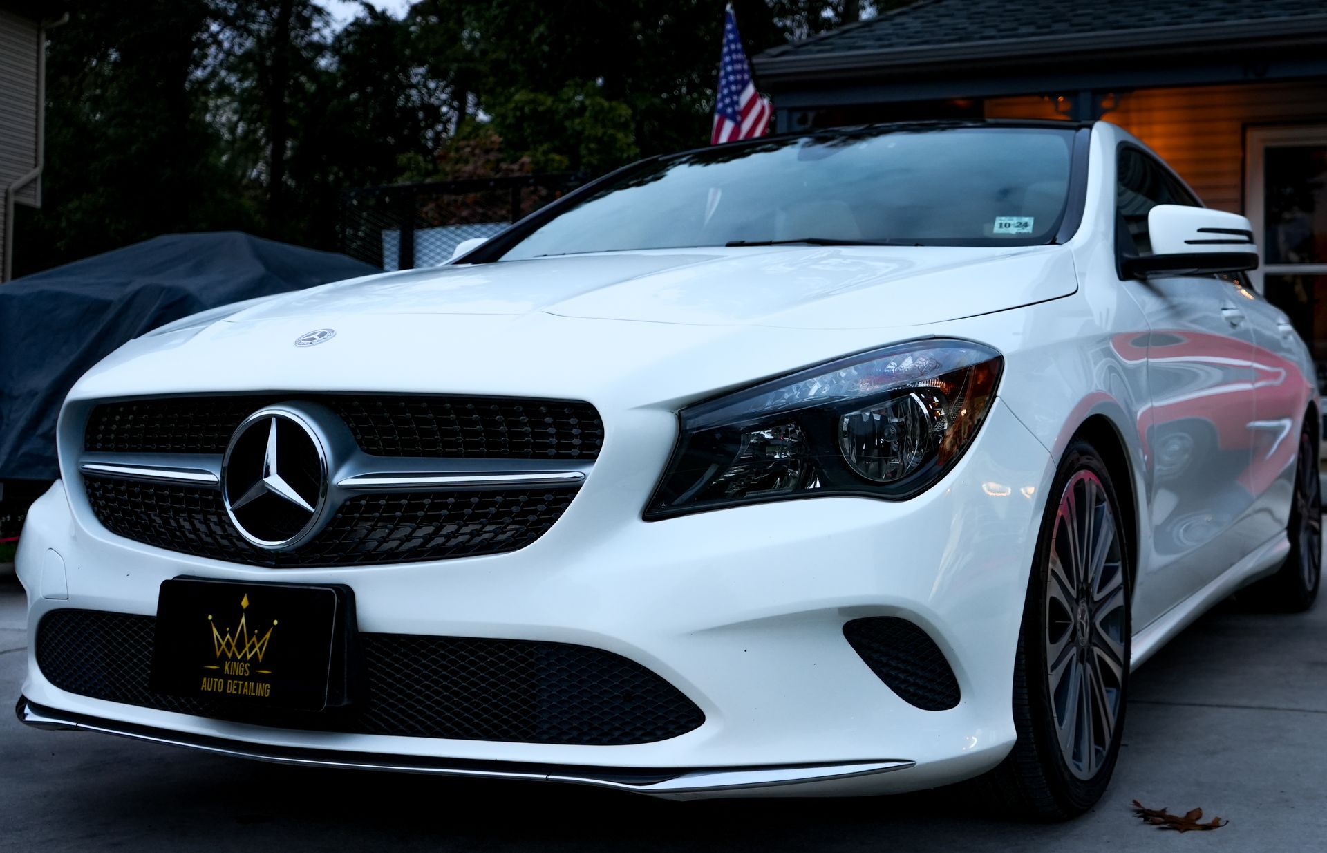 A white mercedes benz is parked in front of a house