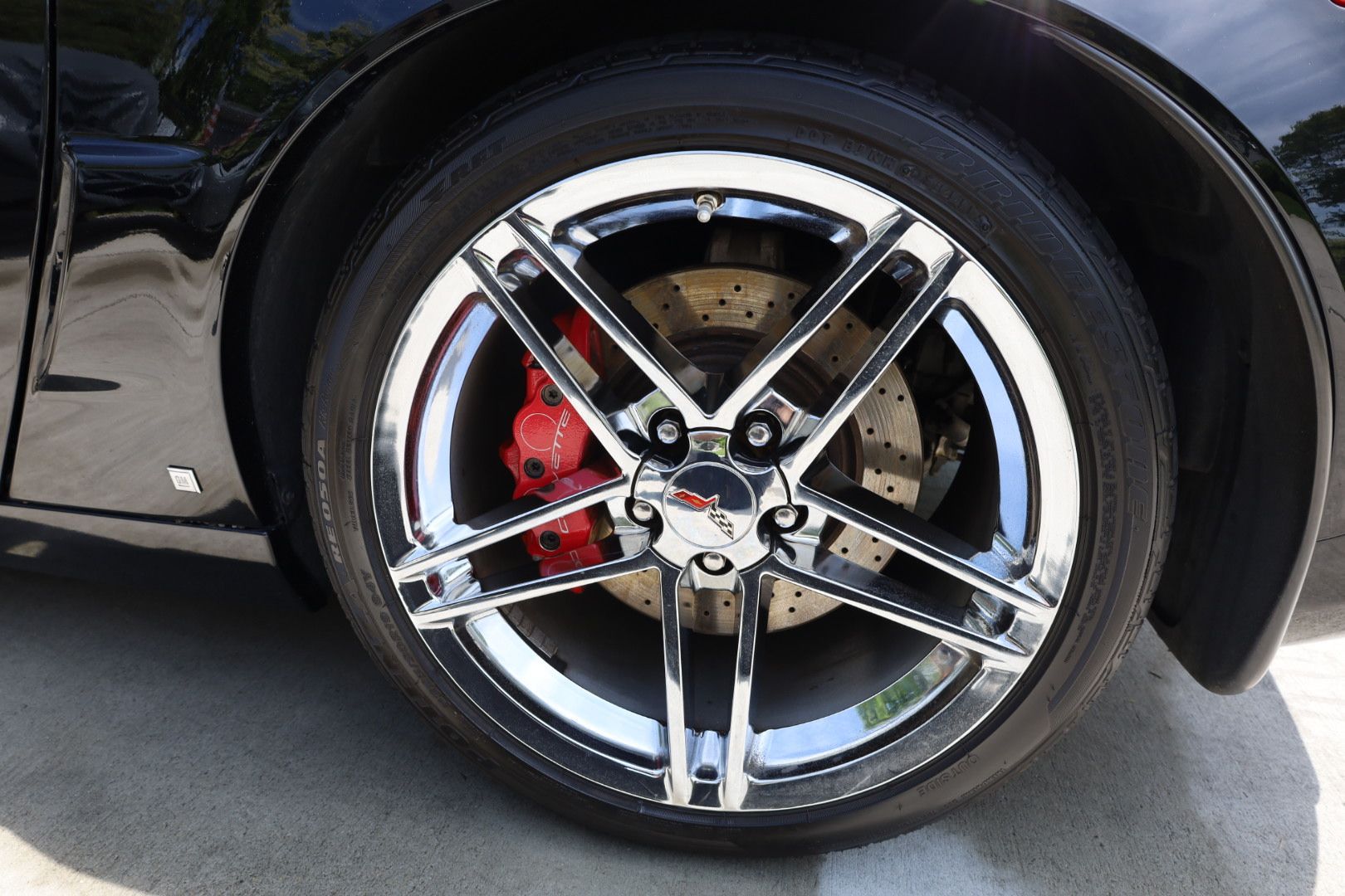 a black corvette with chrome wheels and red brake calipers