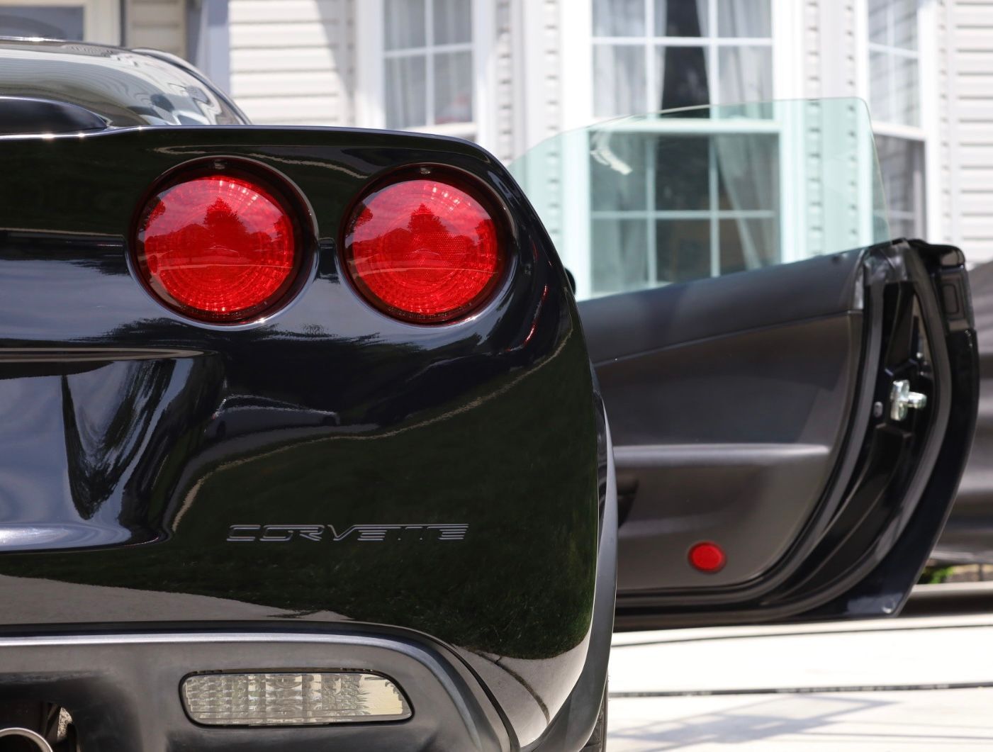 A black corvette is parked in front of a house