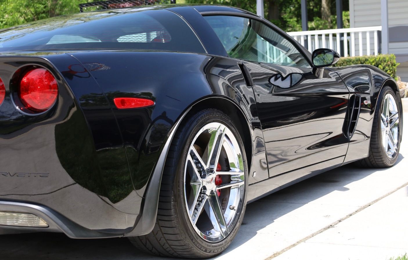 a black corvette is parked in a driveway