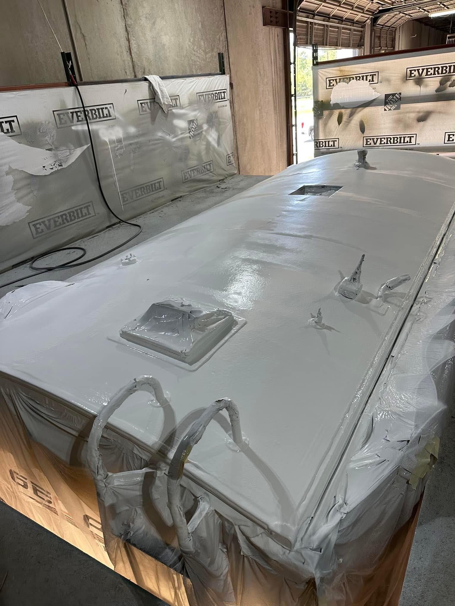 White painted rectangular object, possibly a roof, with ventilation fixtures, indoors.